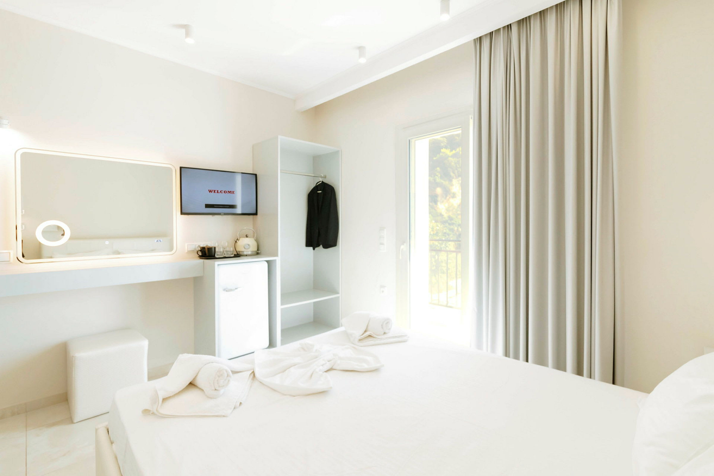 Ett hotellrum med en bäddad säng, TV, kylskåp och garderob. (AI-genererad text)