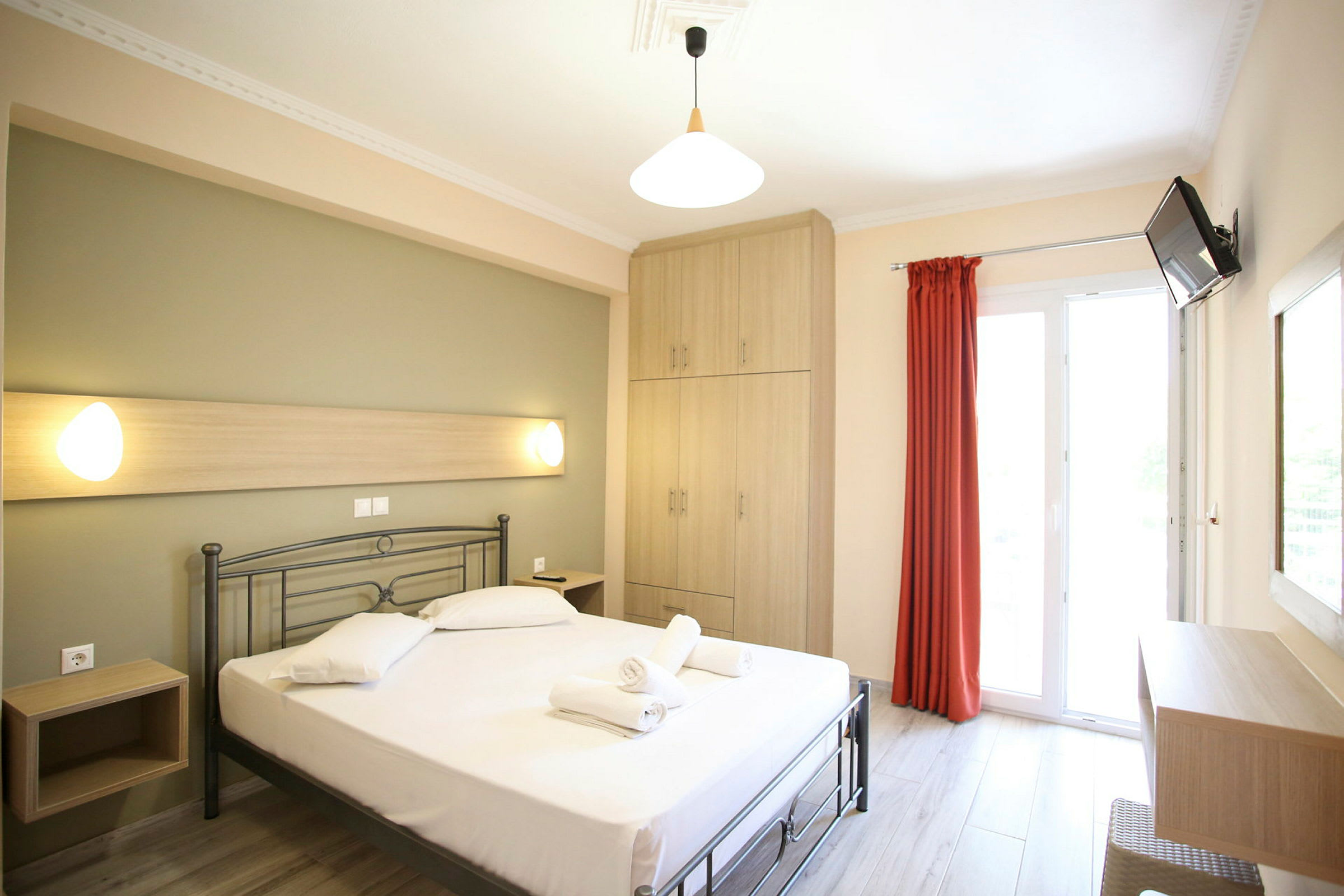 Ett ljust hotellrum med en säng, skåp och en balkongdörr. (AI-genererad text)