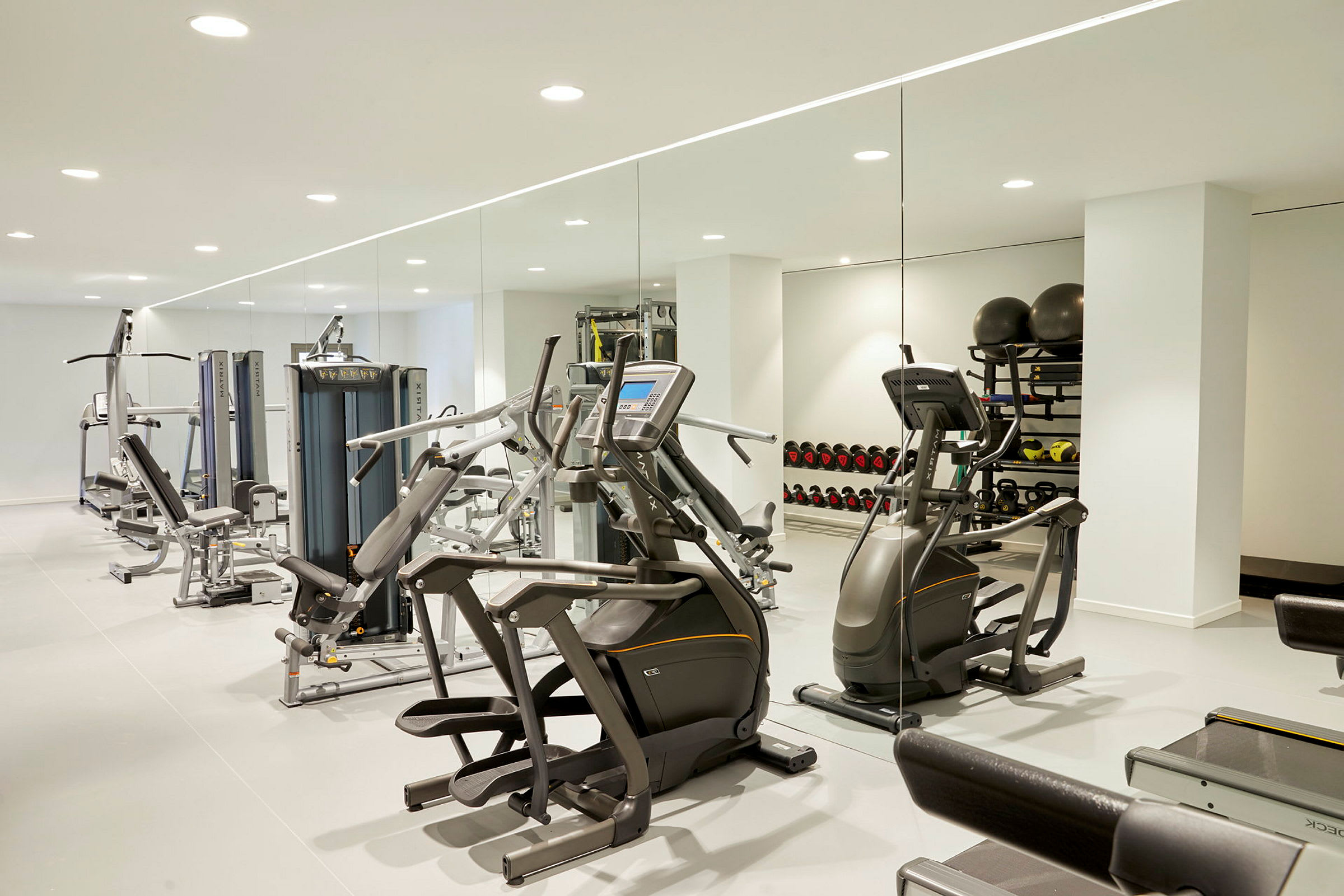 Bild av ett gym med träningsmaskiner, vikter och spegelvägg. (AI-genererad text)
