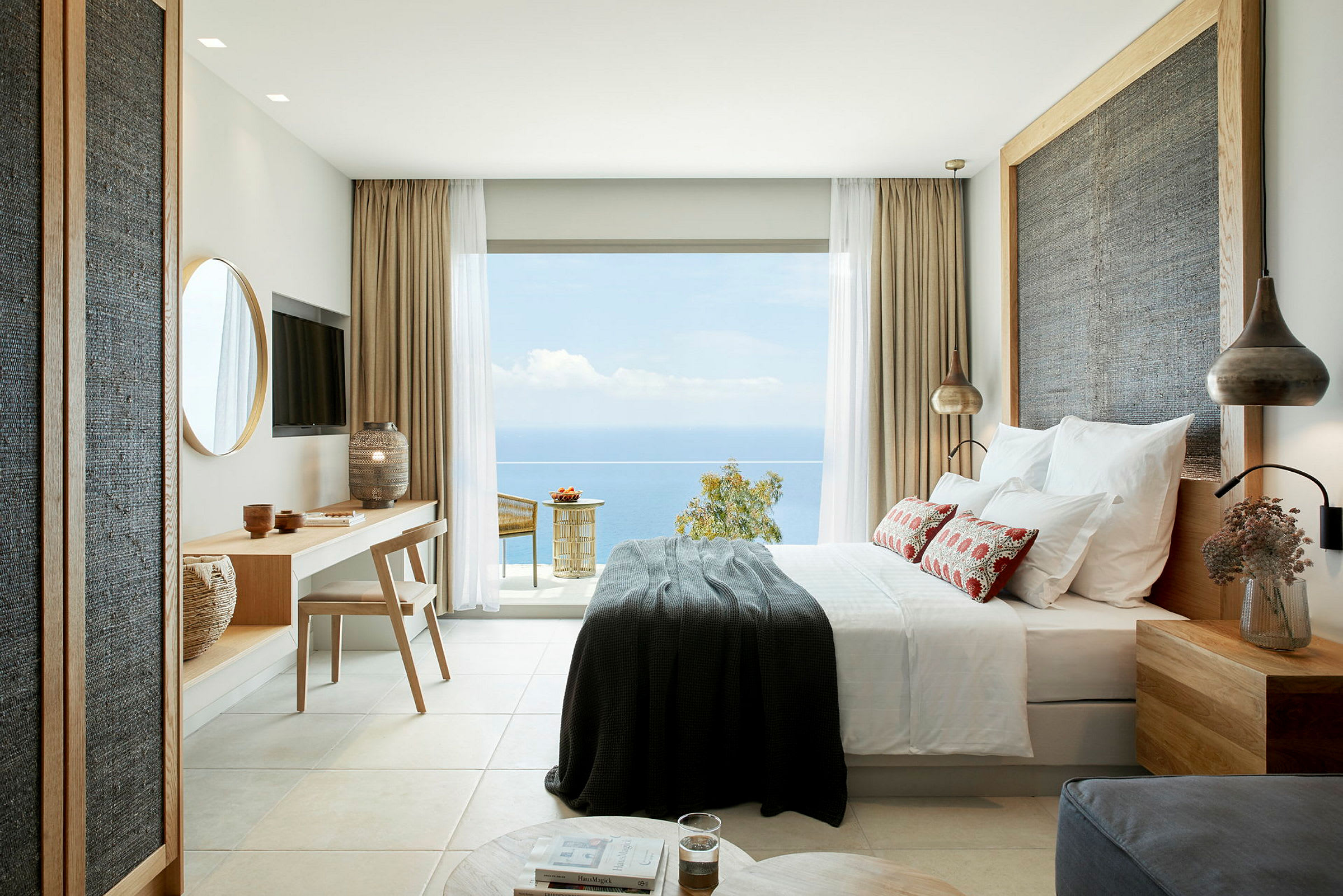 Modernt inredd hotellrum med havsutsikt från en stor glasdörr. (AI-genererad text)