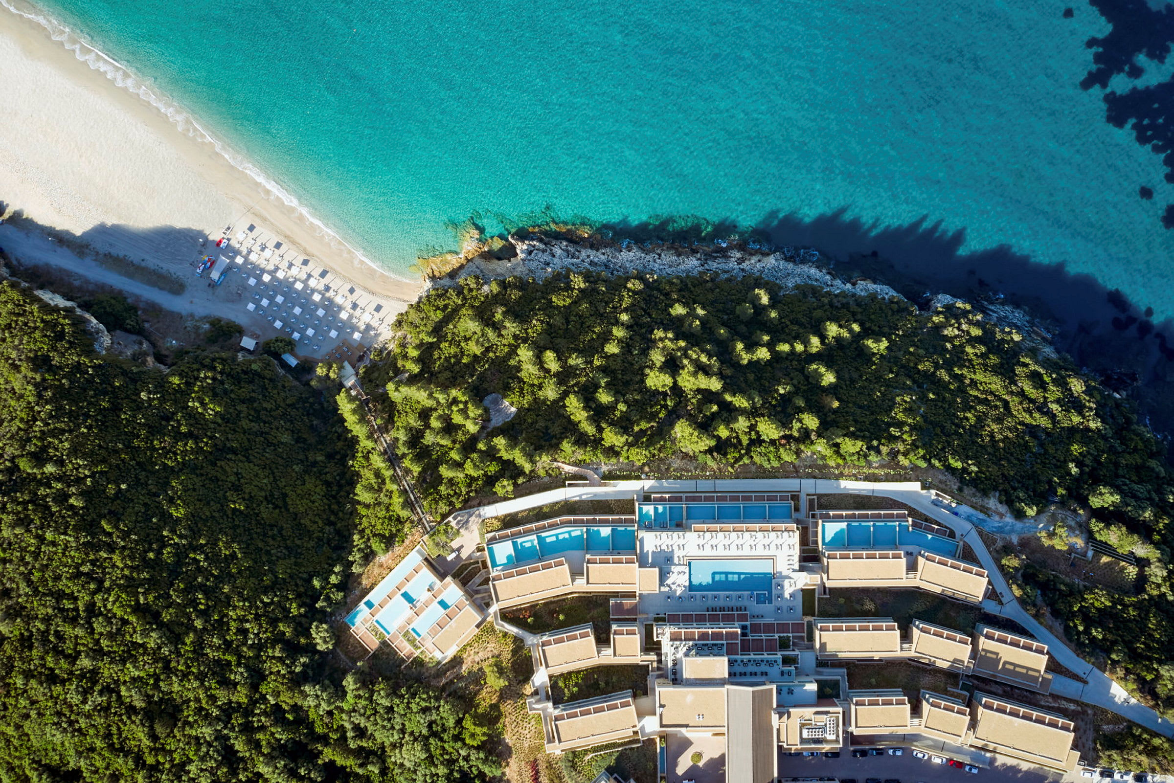 Flygfoto av ett hotellkomplex vid stranden med omgivande växtlighet. (AI-genererad text)