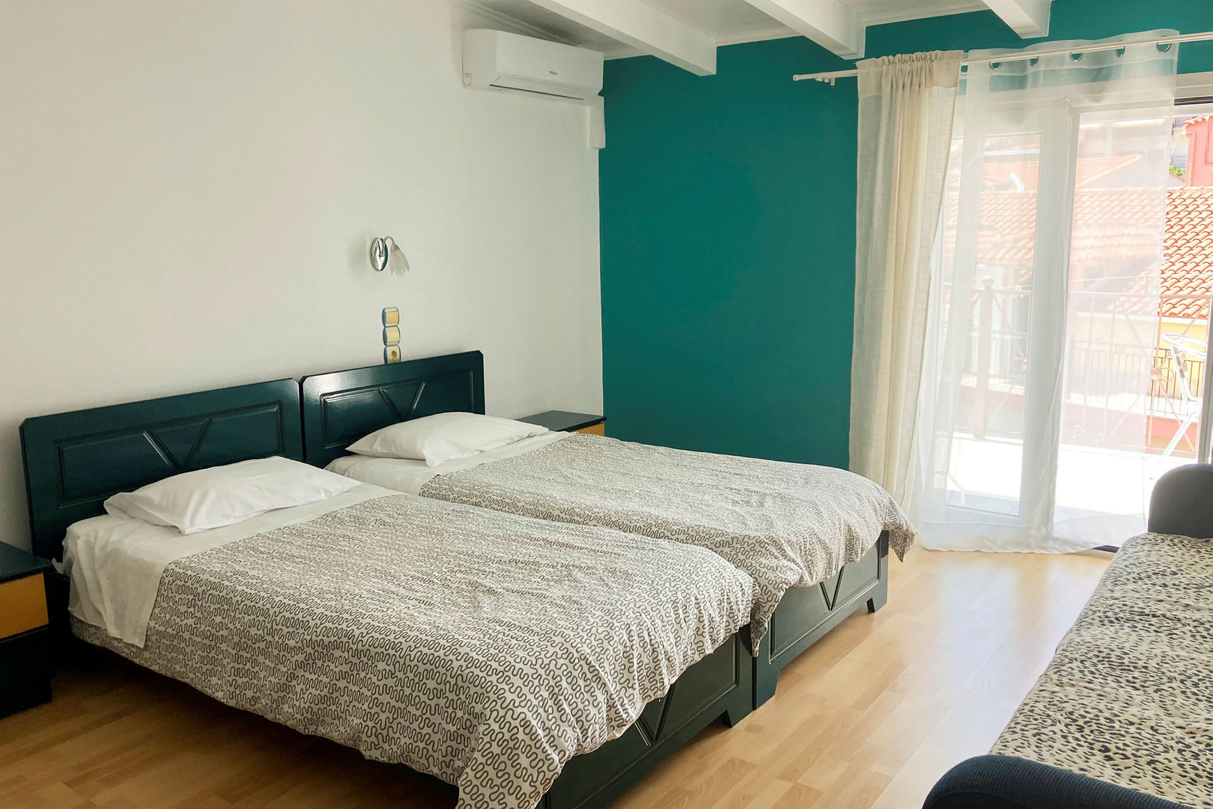 Ett hotellrum med två enkelsängar, en soffa och en balkongdörr. (AI-genererad text)