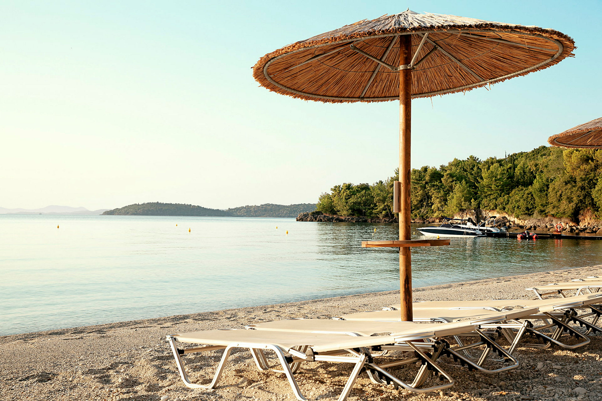 Strand med solstolar och parasoll vid vattenkant. (AI-genererad text)