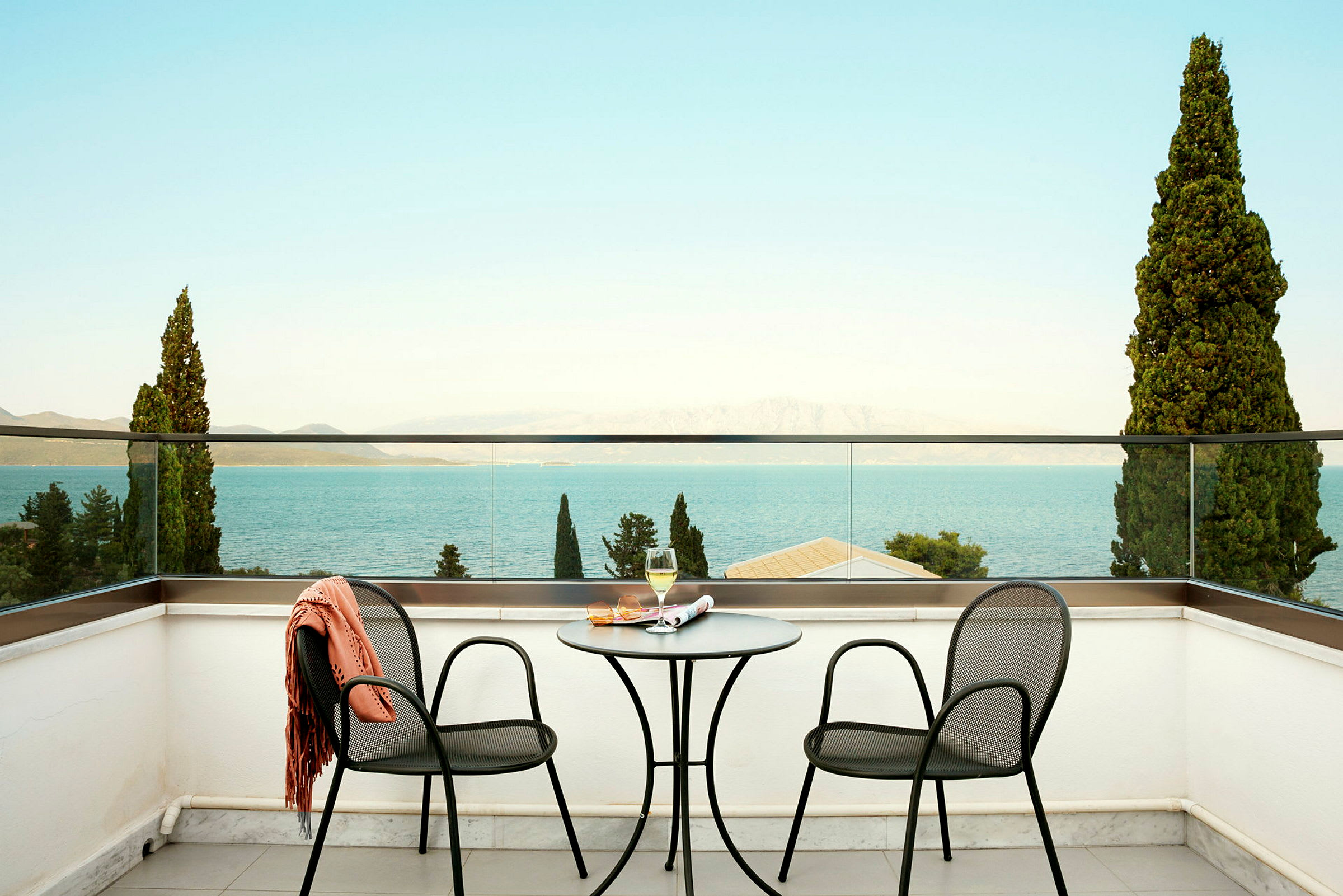 Två stolar och ett bord på en terrass med utsikt över havet. (AI-genererad text)