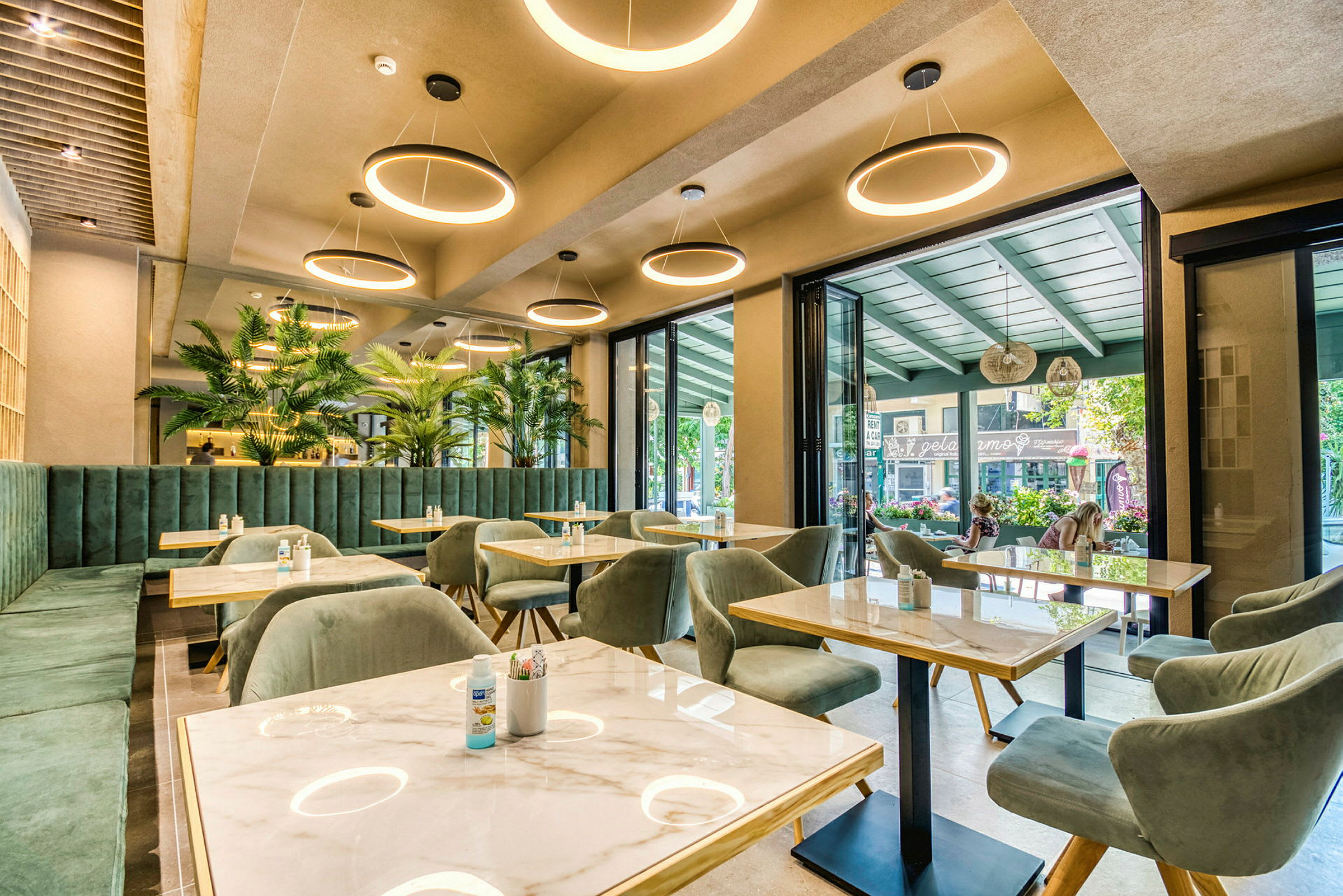 En modern restaurang med gröna möbler och stora fönster. (AI-genererad text)