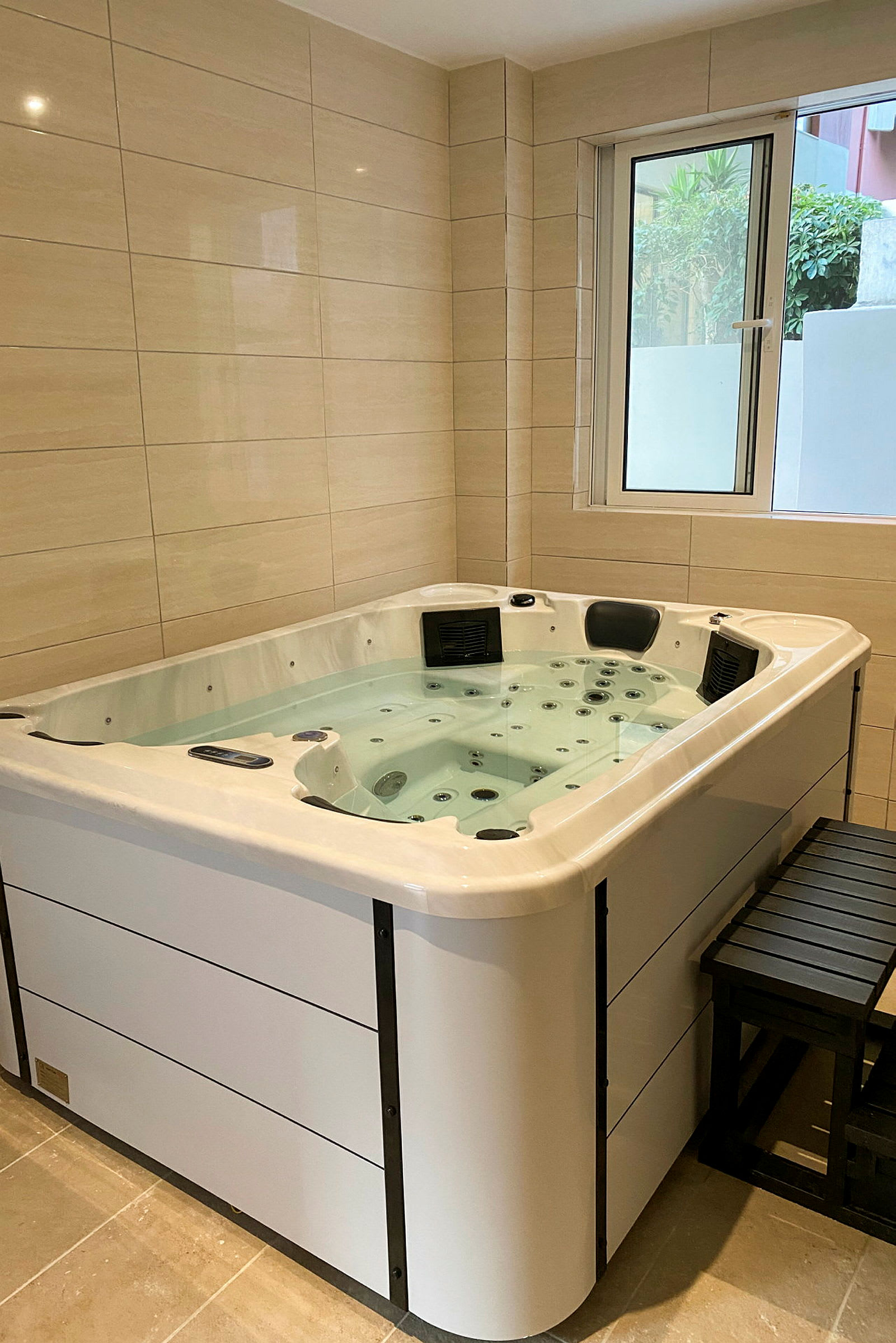 Inomhusjacuzzi med vatten, belägen nära ett fönster. (AI-genererad text)