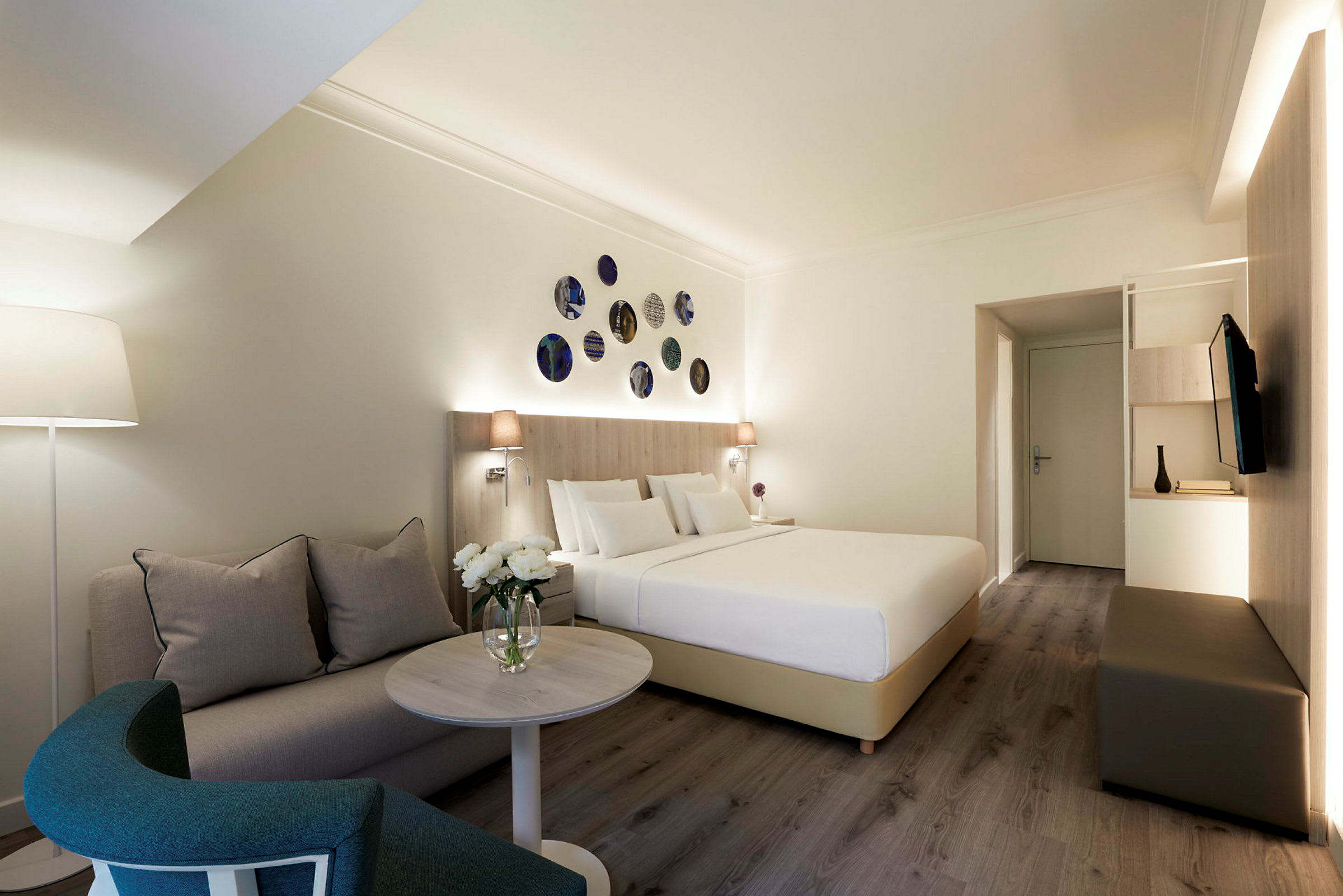 Ett hotellrum med en säng, en soffa och ett soffbord, dekorerat med moderna detaljer. (AI-genererad text)