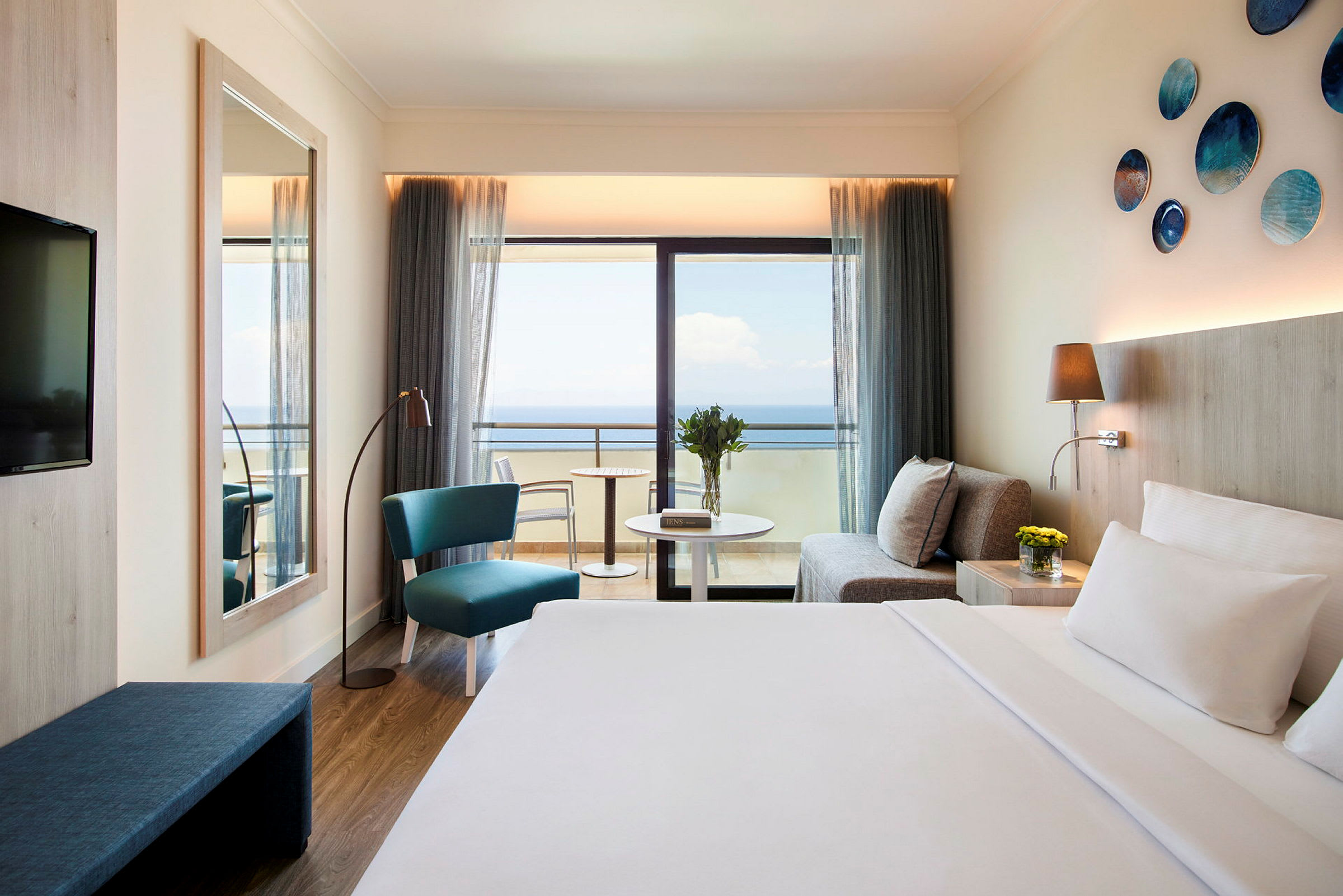 Hotellrum med havsutsikt, soffa, sittplats och säng. (AI-genererad text)