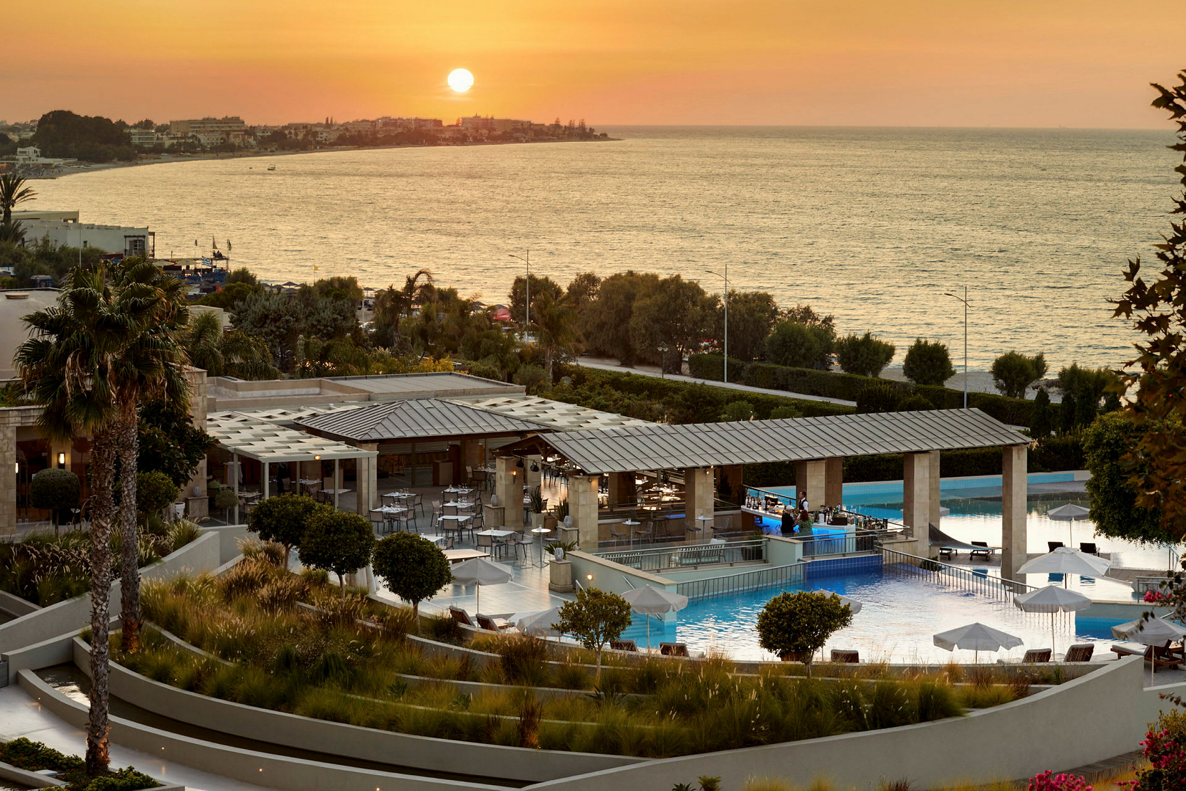 Bild av en hotellanläggning med en pool och utsikt över havet vid solnedgång. (AI-genererad text)