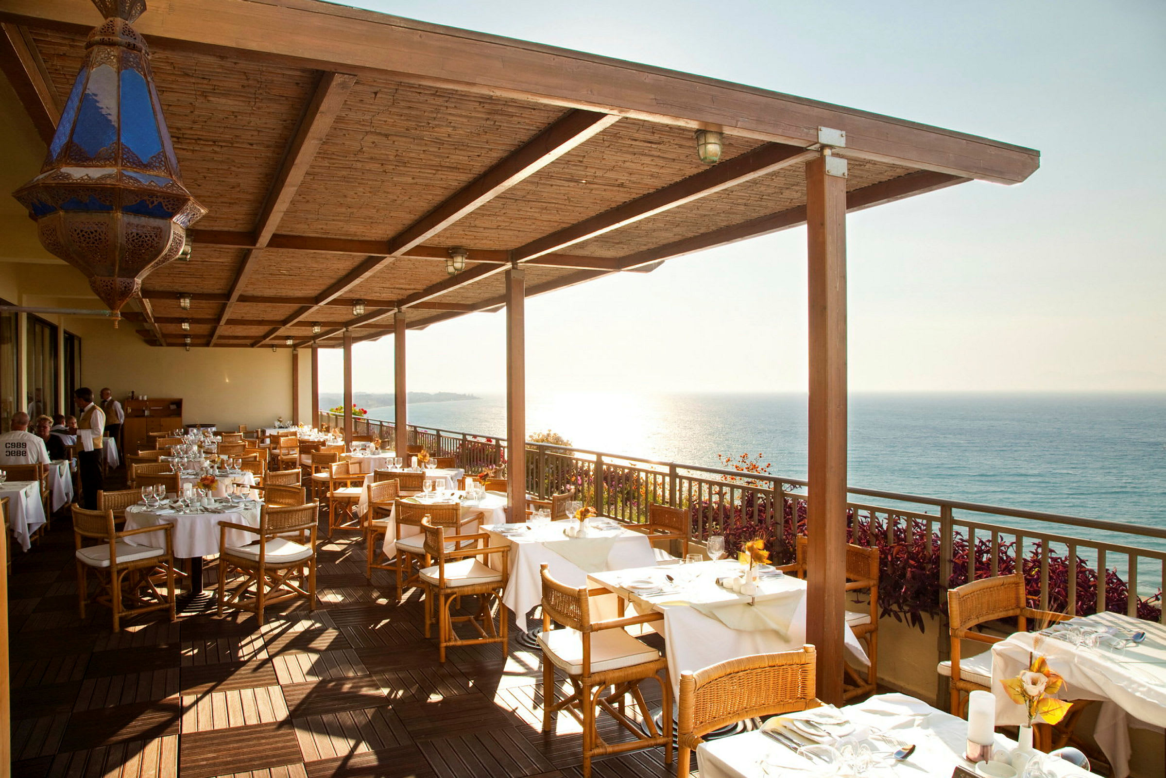 Restaurangterrass med dukade bord och havsutsikt. (AI-genererad text)