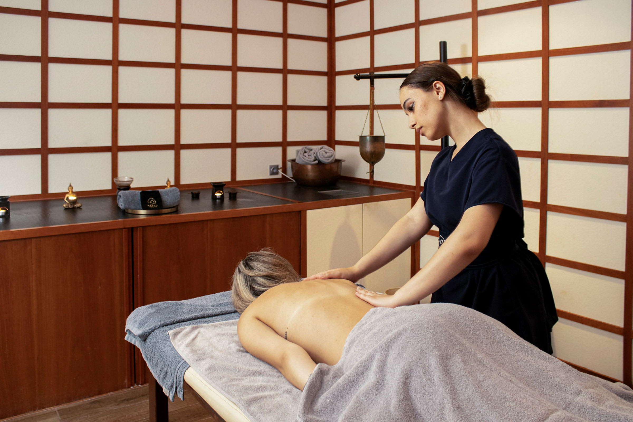 En person får massage i ett spa med asiatisk inspirerat inredning. (AI-genererad text)
