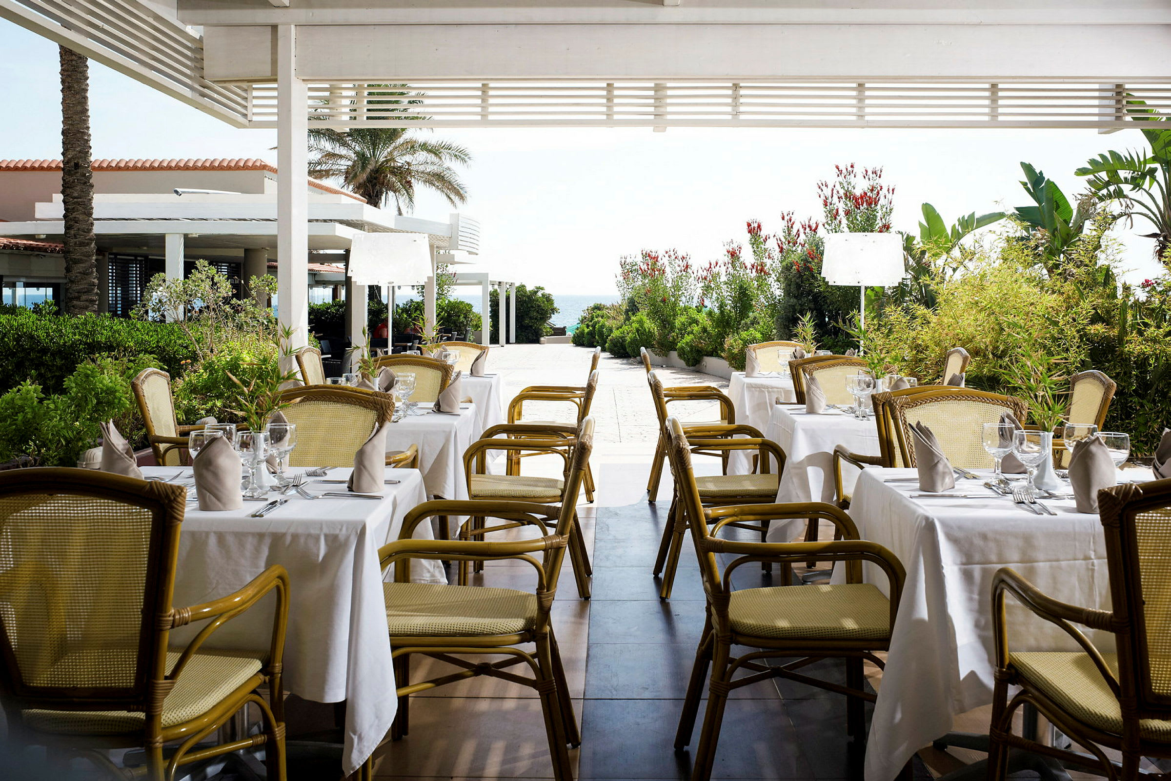 Restaurang med dukade bord under en pergola. (AI-genererad text)