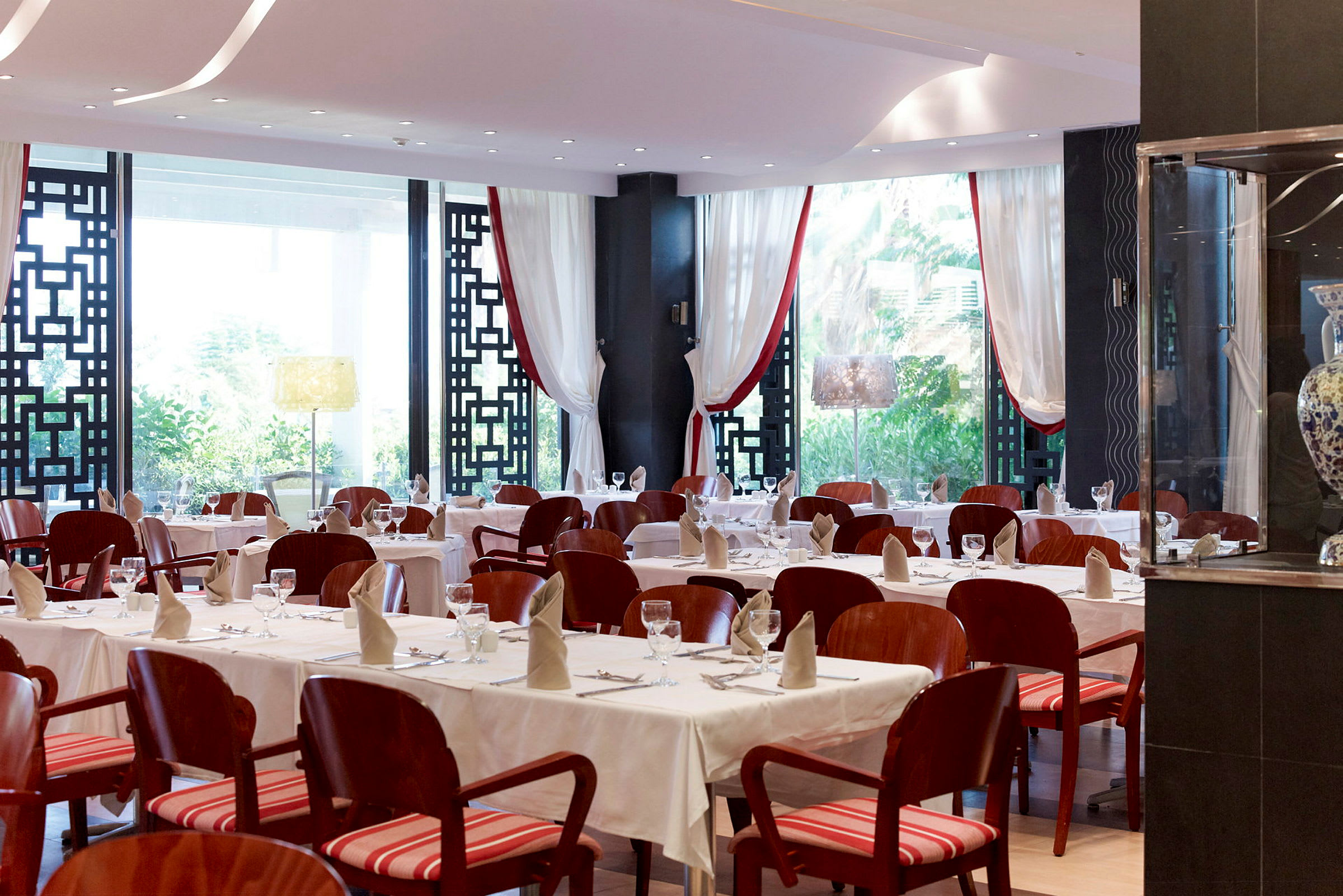 En elegant restaurang med dukade bord och röda stolar. (AI-genererad text)