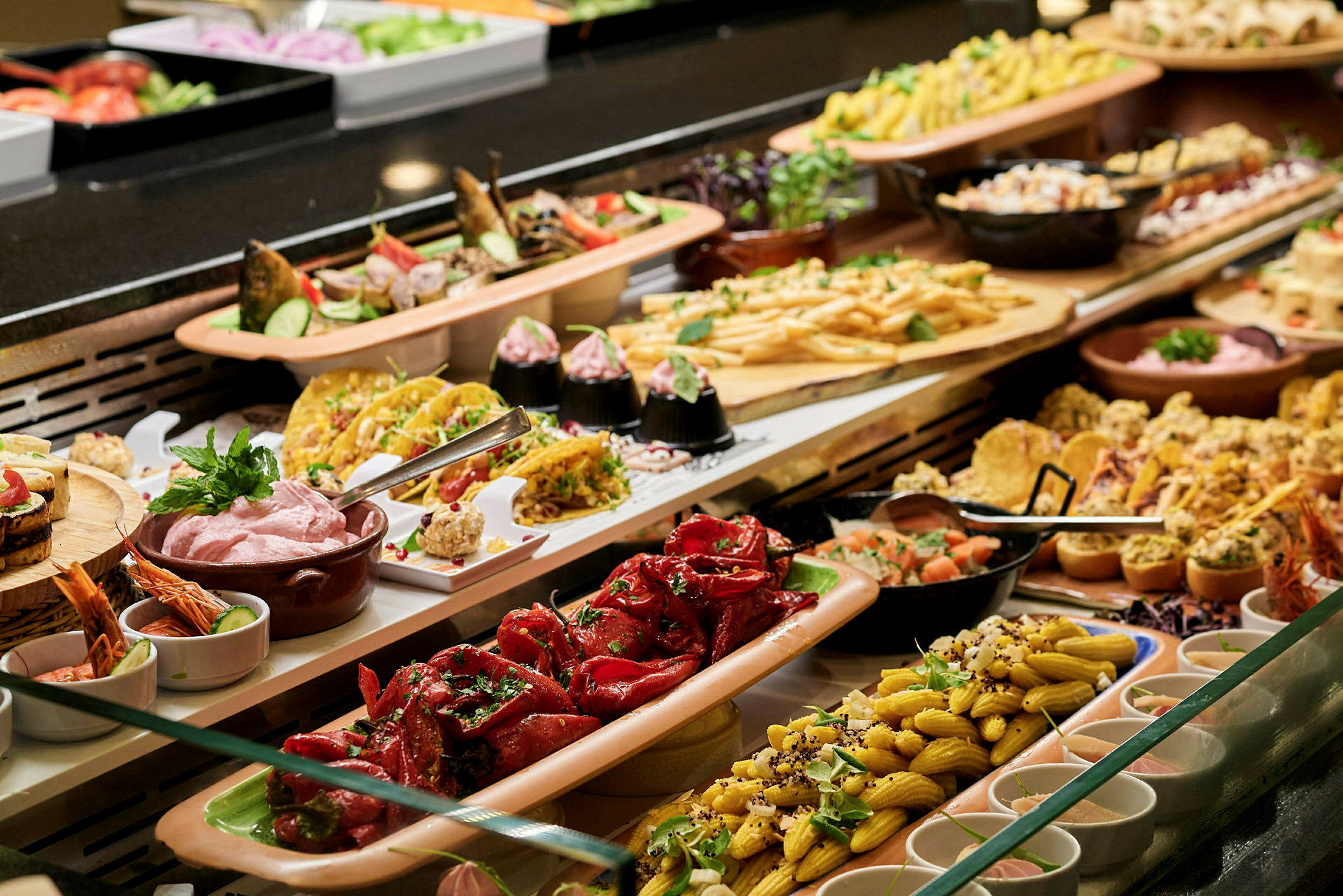 Ett buffébord med olika maträtter och sallader upplagt på fat och skålar. (AI-genererad text)