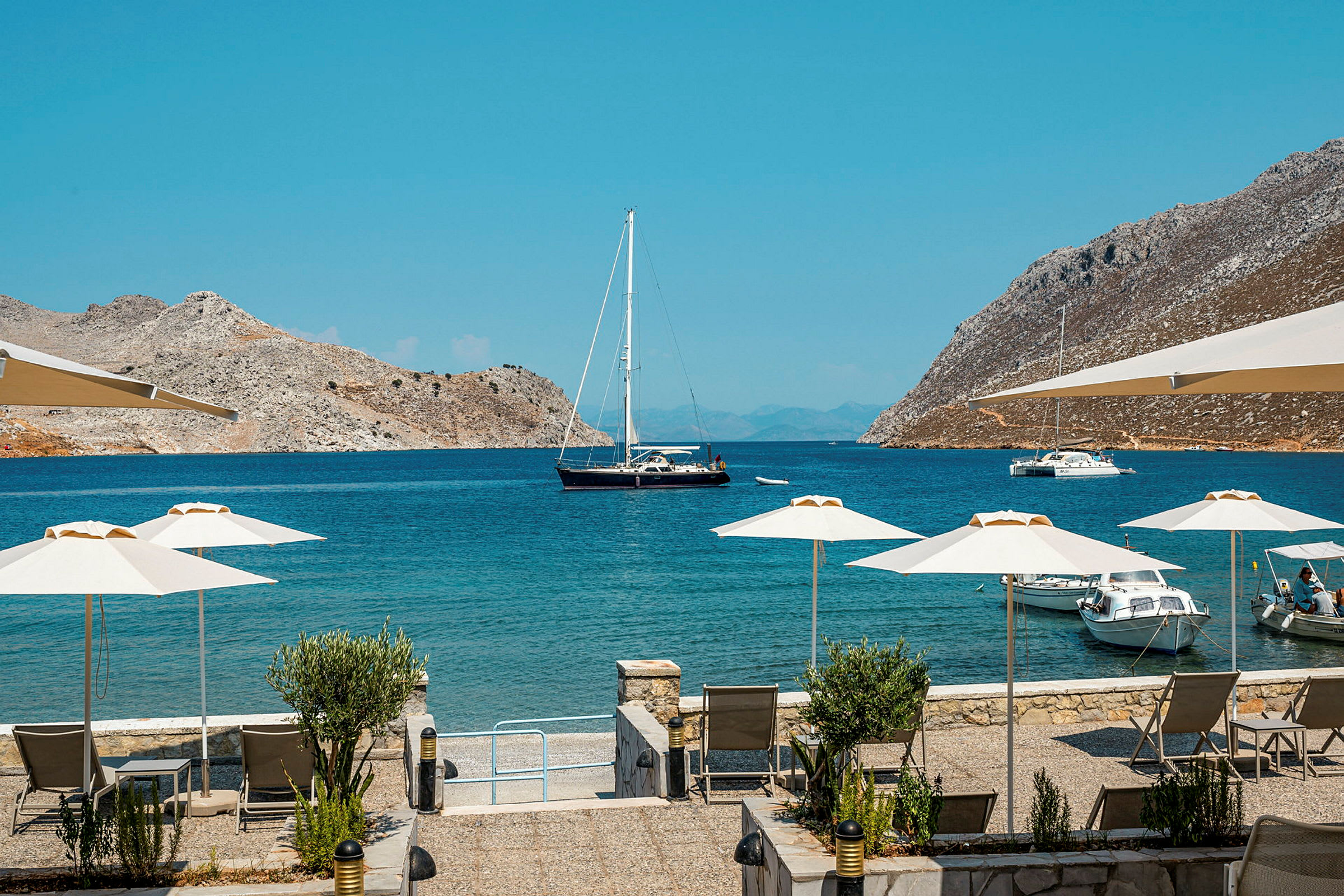 Strandutsikt med parasoller och båtar vid en turkos blå vik. (AI-genererad text)