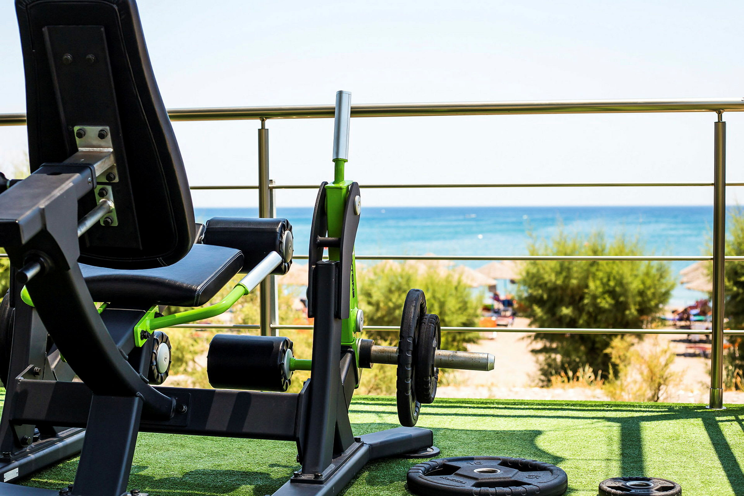 Gymutrustning i förgrunden med utsikt över stranden och havet. (AI-genererad text)