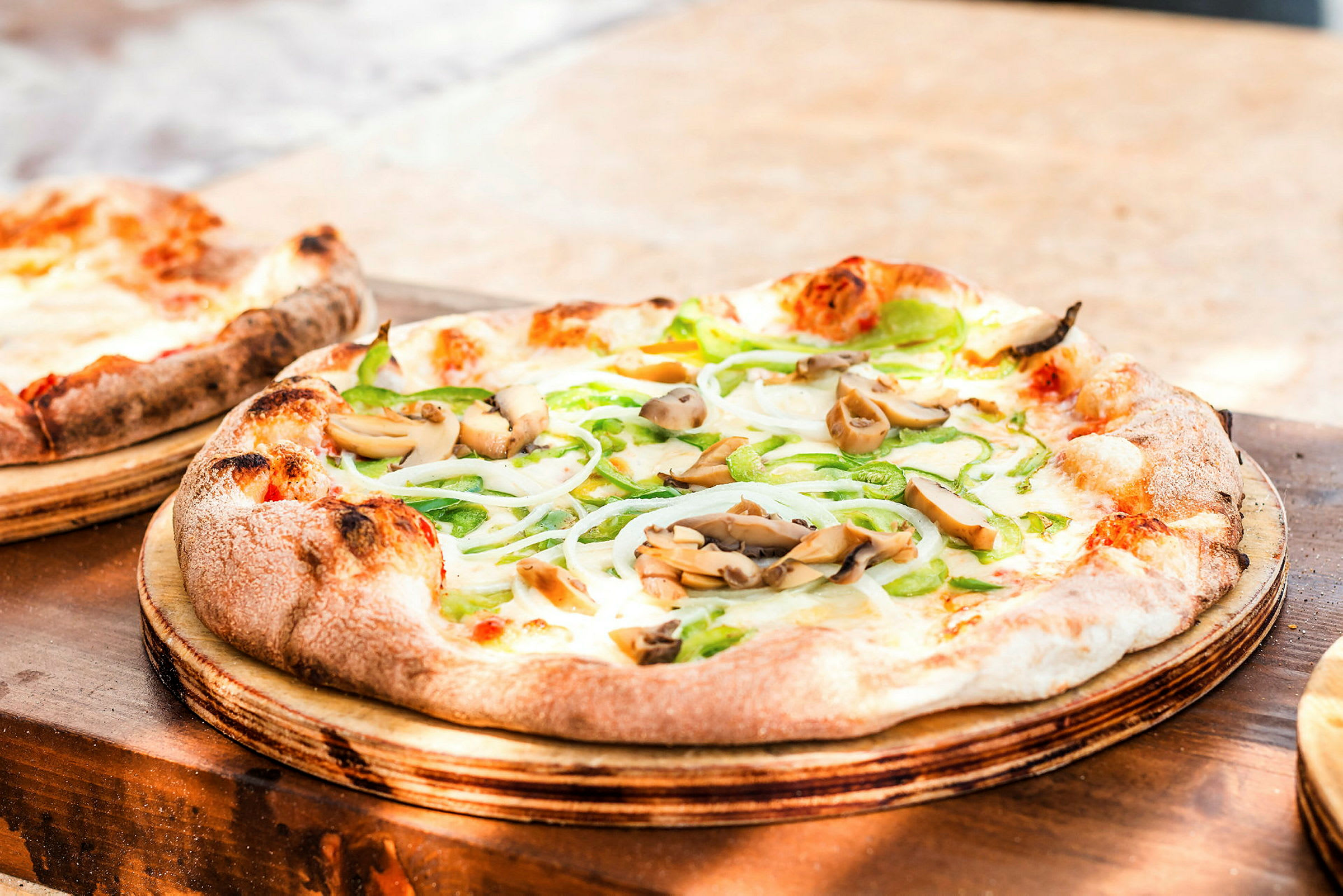 En närbild på en pizza med grönsaker och svamp, serverad på en träbricka. (AI-genererad text)