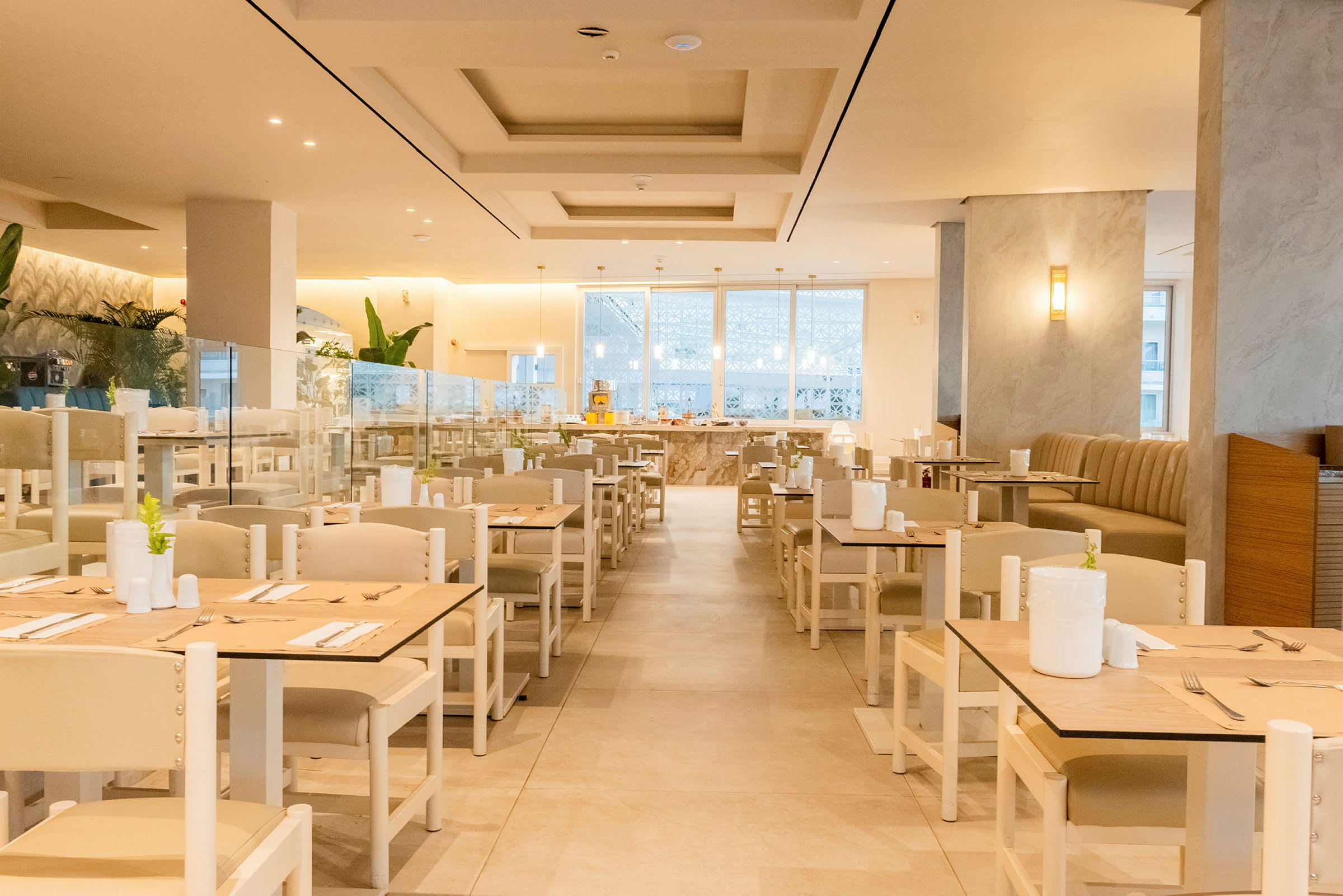 En elegant matsal med ljus inredning, dukade bord och stolar arrangerade i rader. (AI-genererad text)