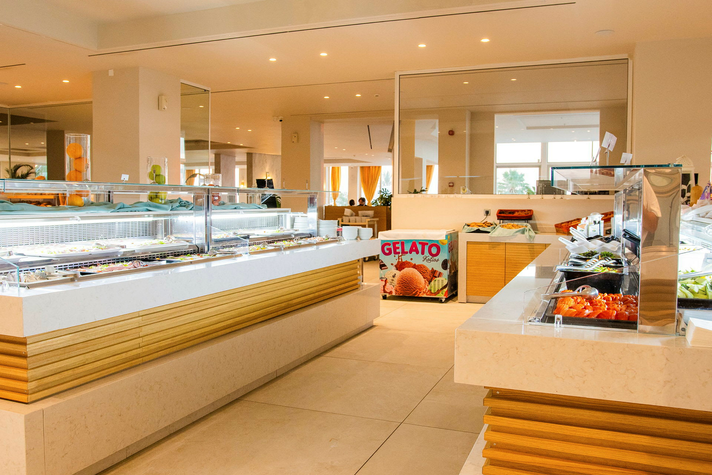 Bild av en hotellbuffé med flera matstationer fyllda med olika rätter och en gelatoförsäljning synlig i bakgrunden. (AI-genererad text)
