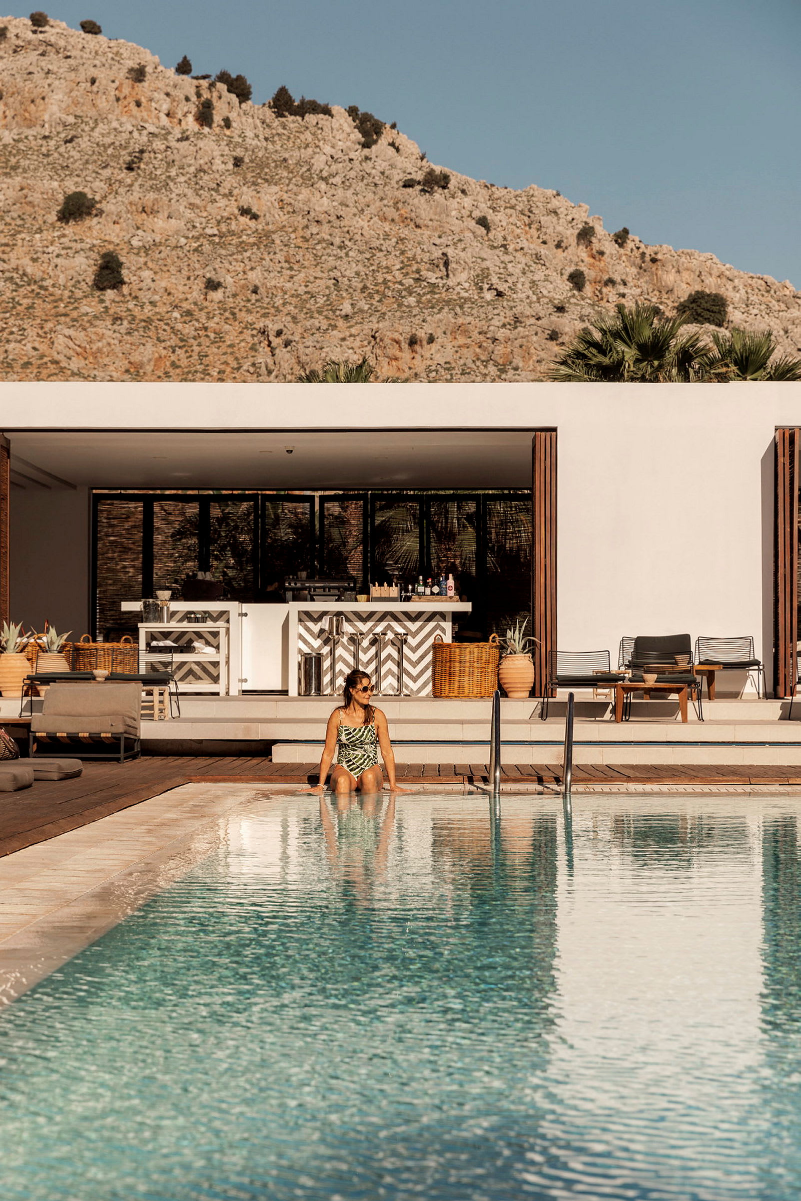 En person sitter vid en pool med berg i bakgrunden. (AI-genererad text)