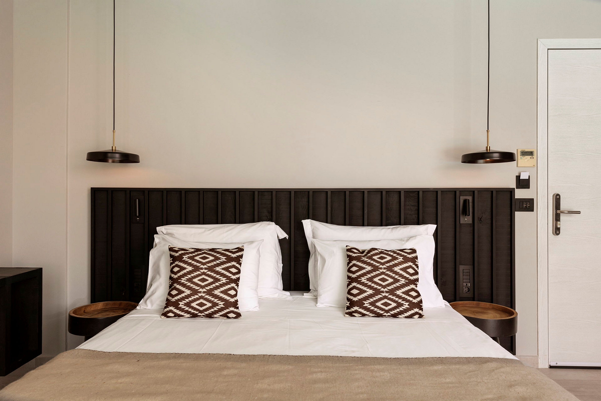 En bädd med två kuddar i ett hotellrum. (AI-genererad text)