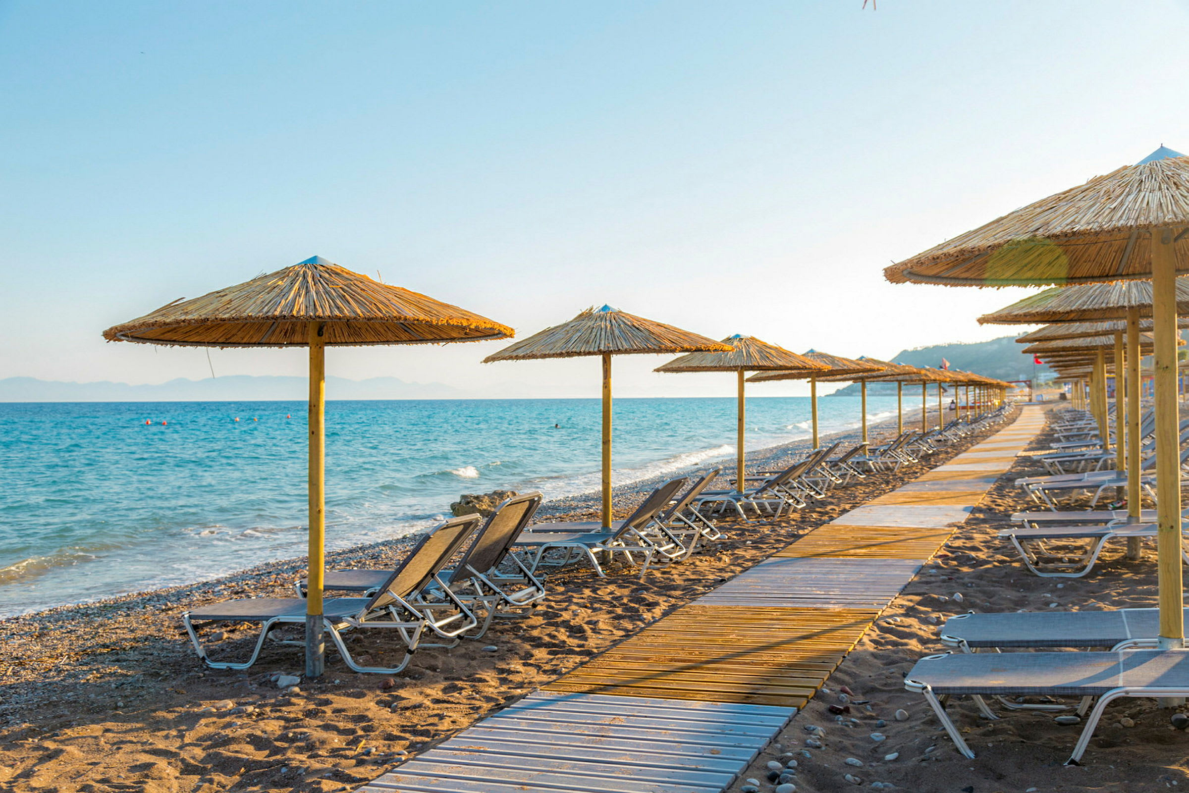 Solstolar och parasoller på en strand vid havet. (AI-genererad text)