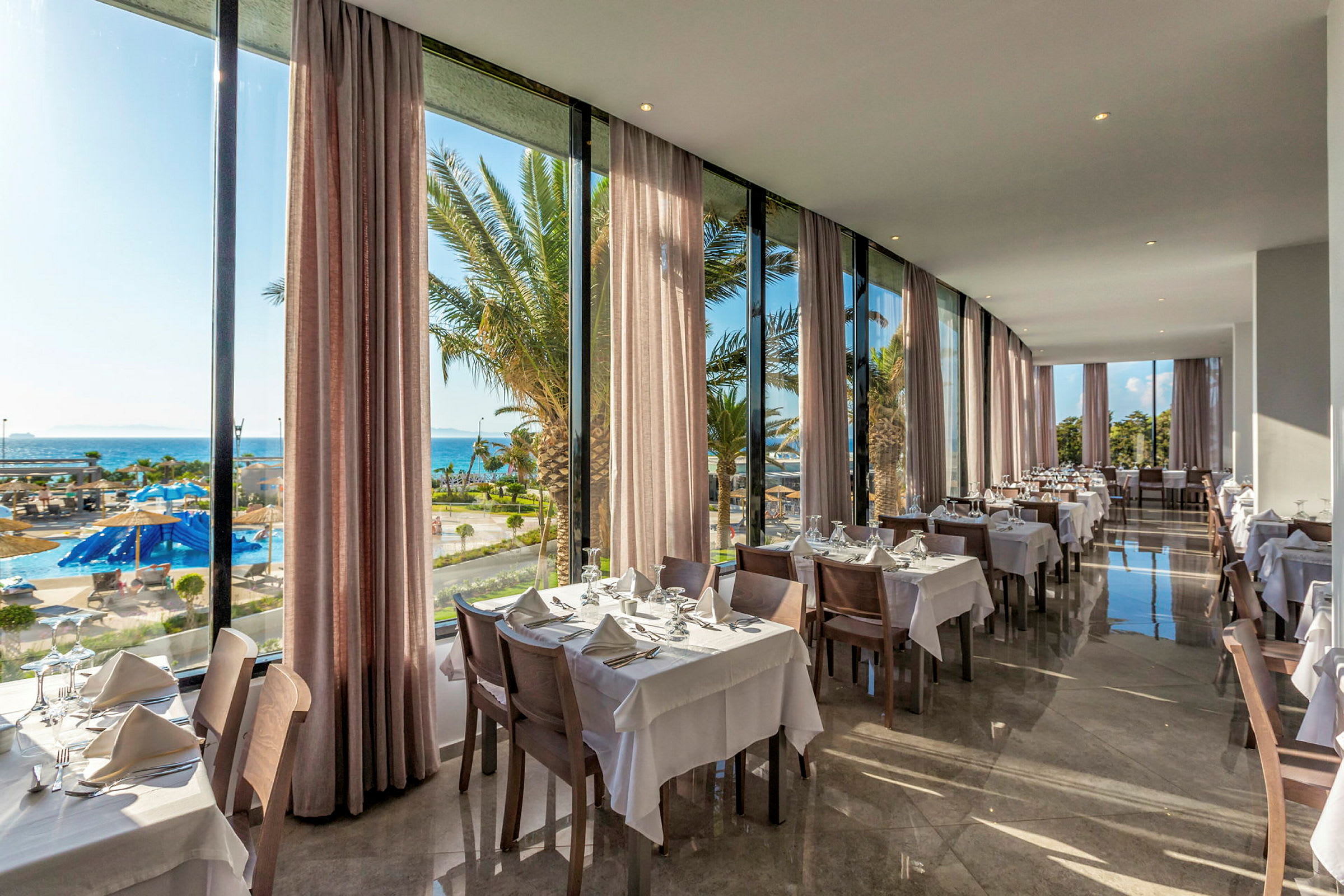Restaurang med dukade bord och utsikt över pool och hav. (AI-genererad text)