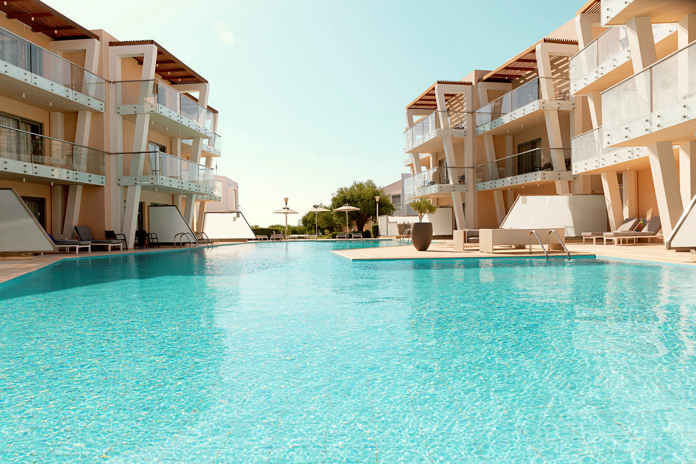En swimmingpool omgiven av moderna byggnader med tillhörande altaner. (AI-genererad text)