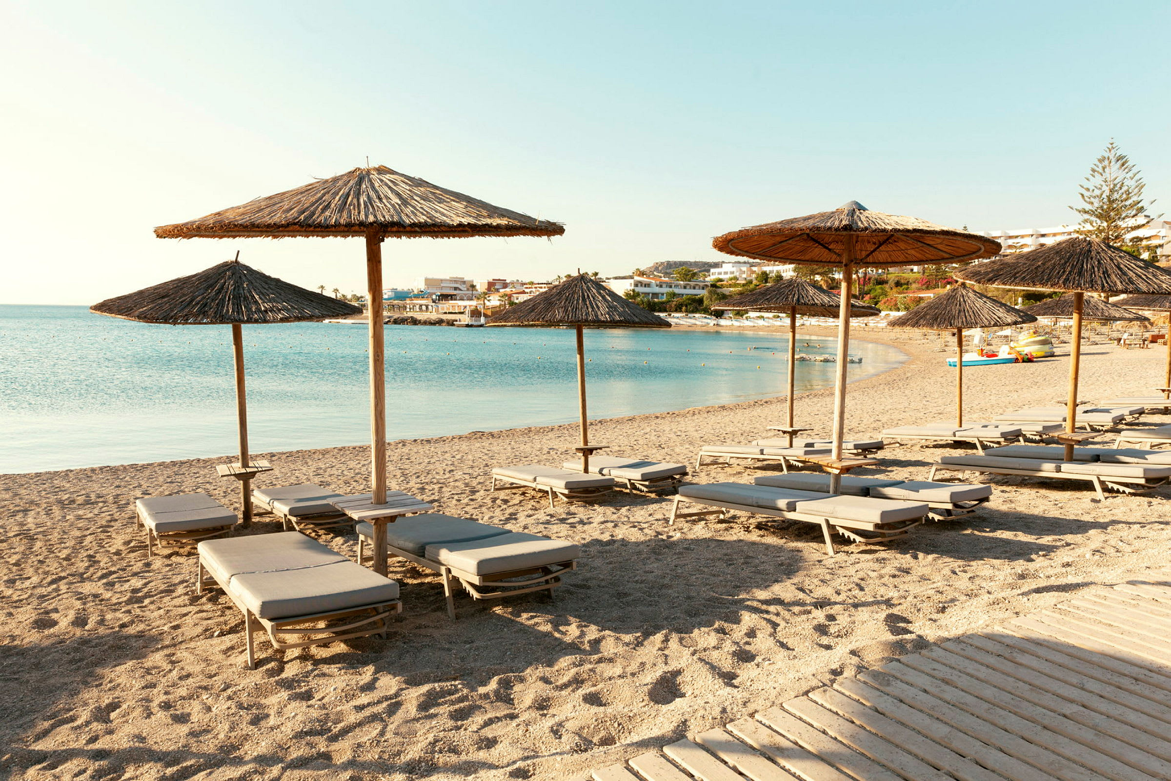 Solstolar och parasoller på en sandstrand med havet i bakgrunden. (AI-genererad text)