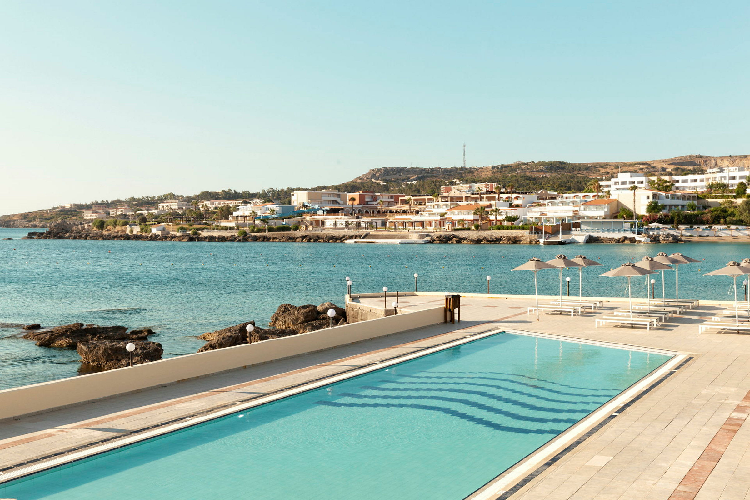 Bild av en pool med utsikt över havet och en kuststad. (AI-genererad text)