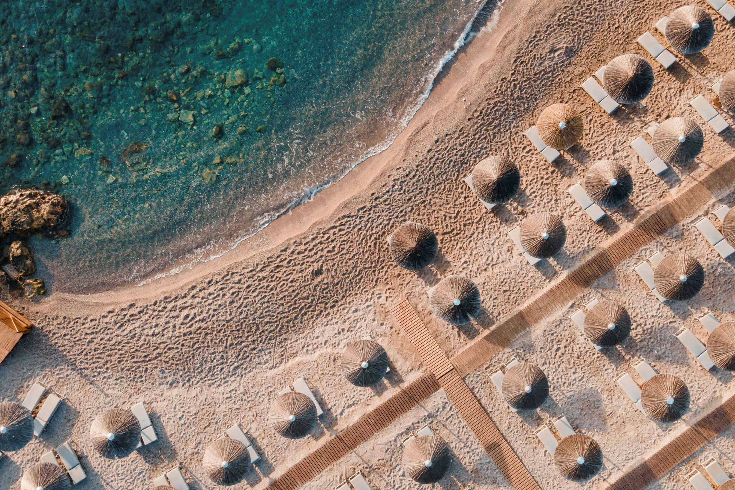 Flygfoto av en sandstrand med parasoller och solstolar. (AI-genererad text)