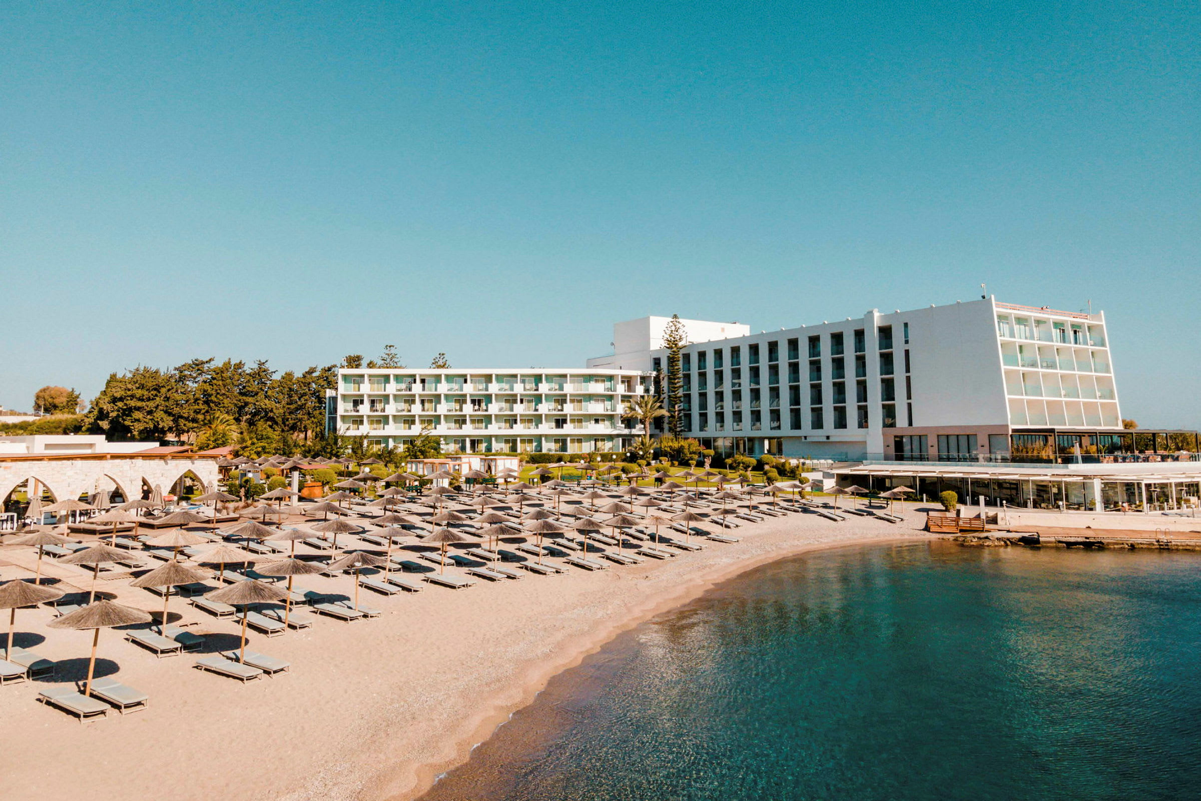 Vy över hotell och stranden med solstolar och parasoller. (AI-genererad text)