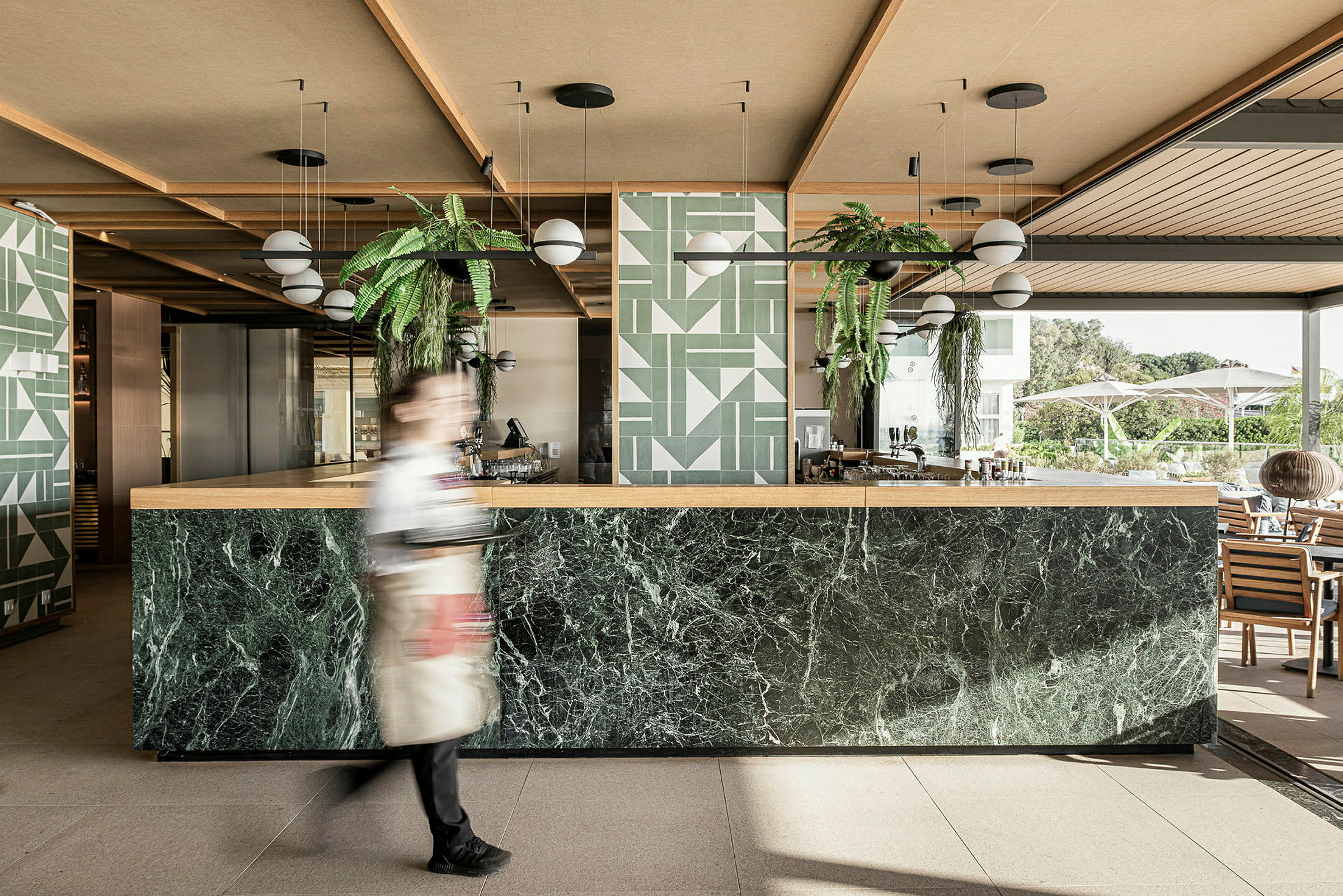 En modern hotellbar med marmordisken och gröna växtdekorer. (AI-genererad text)