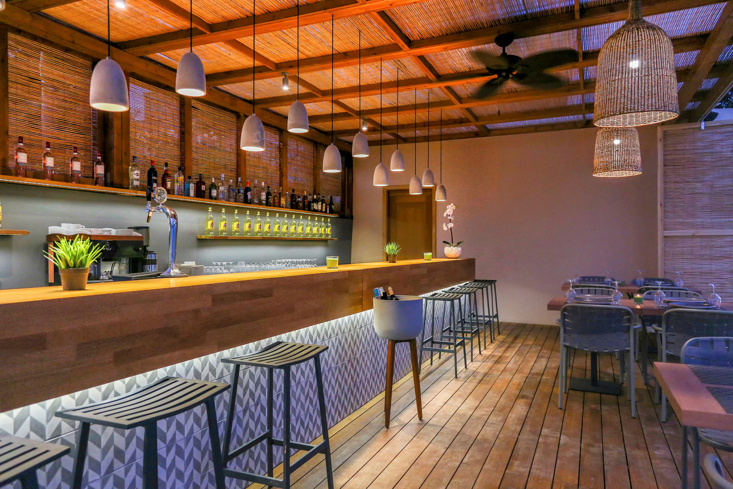 En modern bar med träytor, belysning, flaskhyllor och barstolar. (AI-genererad text)