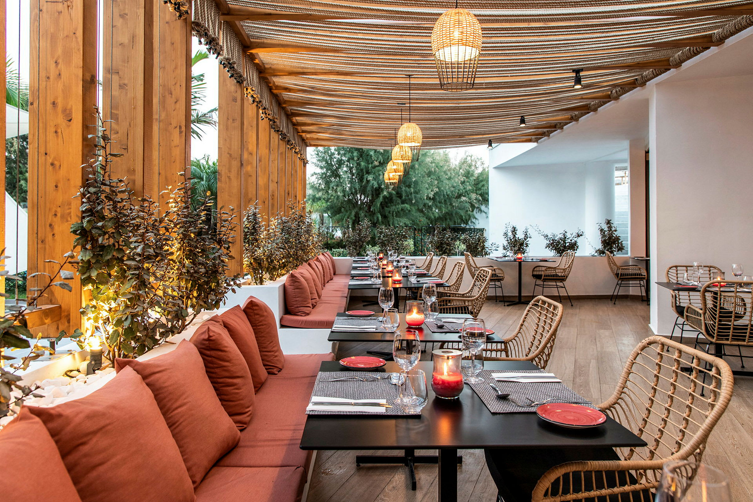 Restaurang med träbeklädd interiör, röda kuddar vid sittplatser och bord med dekorationer. (AI-genererad text)