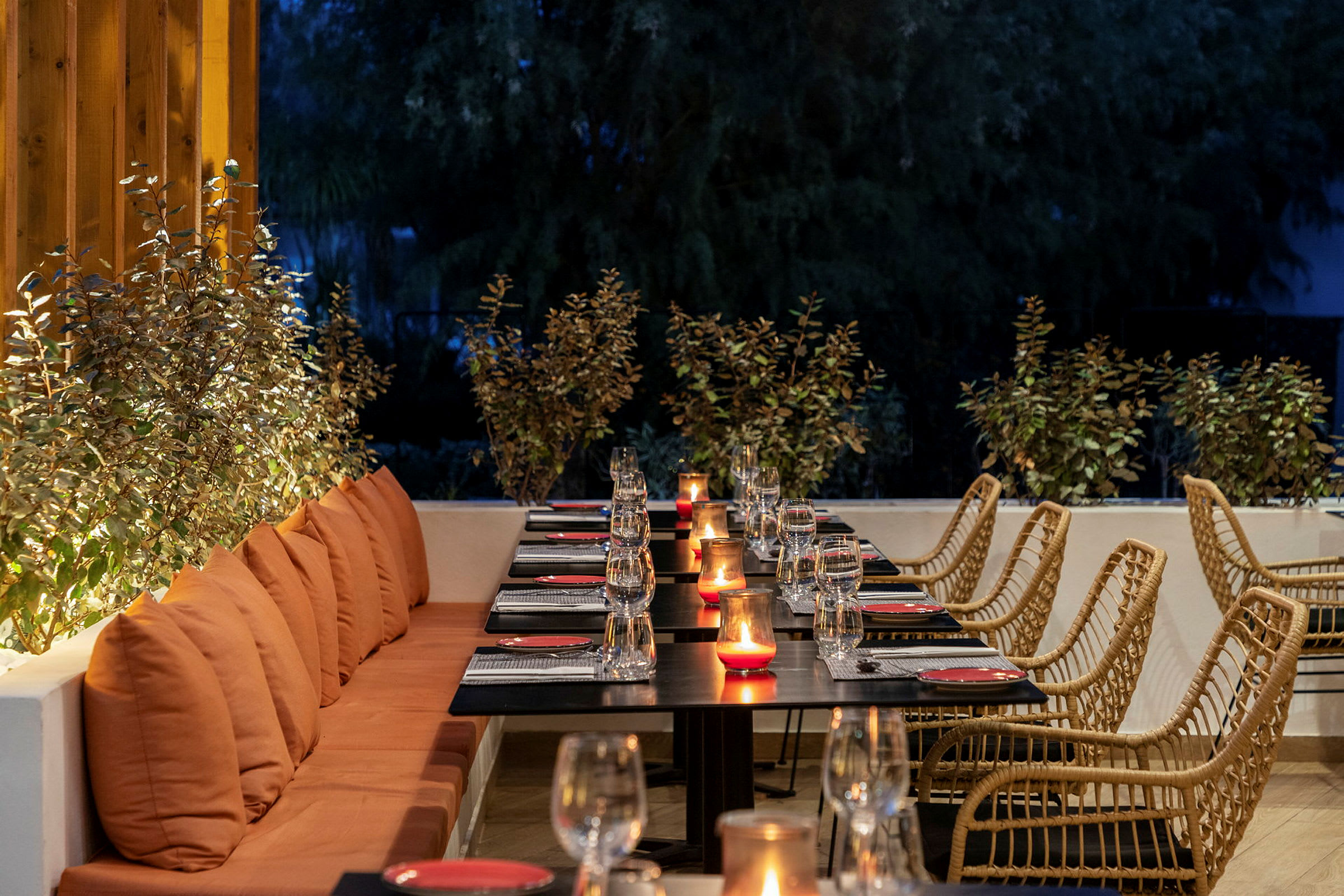 En restaurang med dukade bord och tända ljus på en uteplats. (AI-genererad text)
