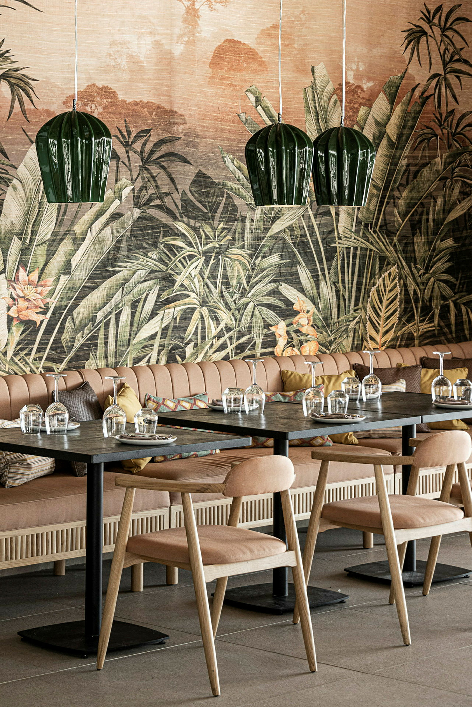 En restaurang med bord och stolar framför en vägg med tropiskt motiv. (AI-genererad text)