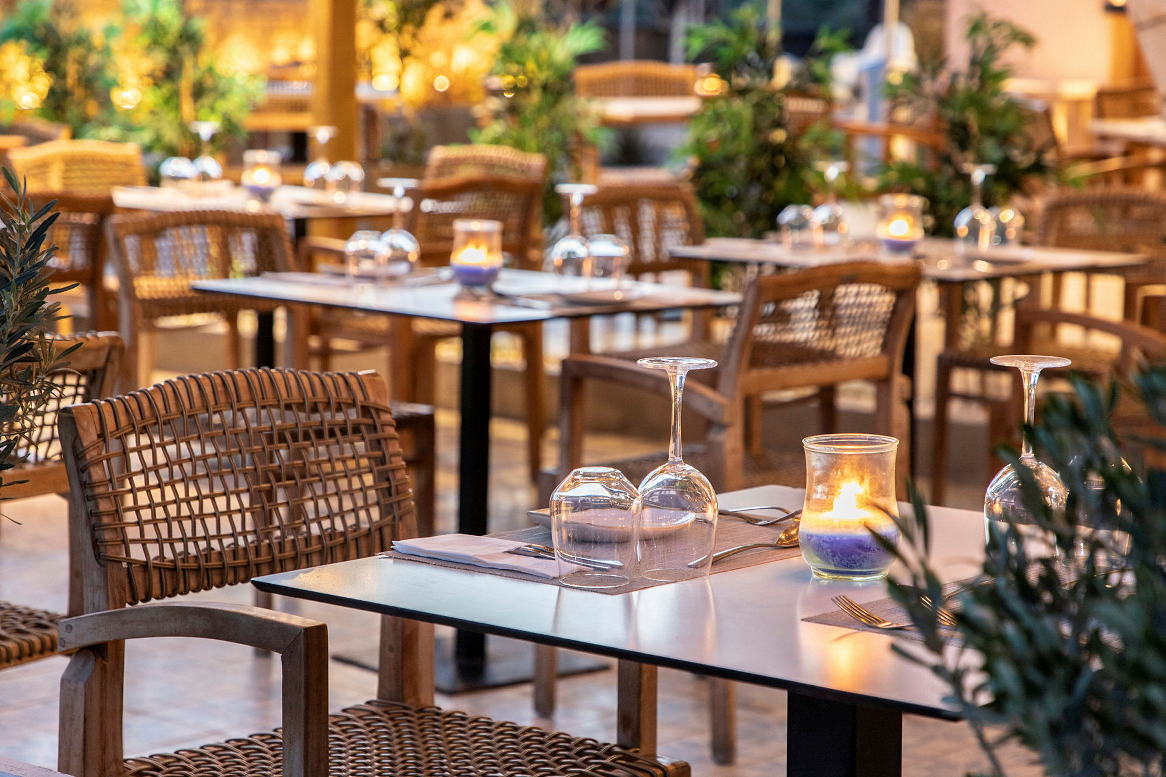En utomhusrestaurang med dukade bord, vinglas och ljus. (AI-genererad text)