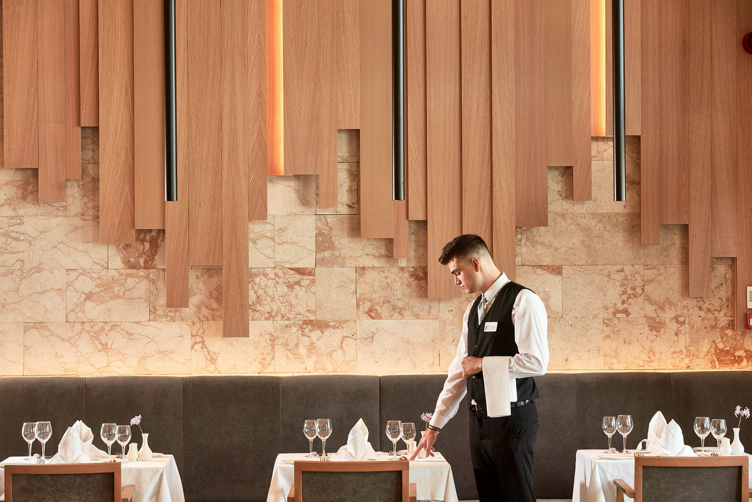 En elegant restaurangmiljö med dukade bord, glas och servetter, och träpaneler på väggarna. (AI-genererad text)