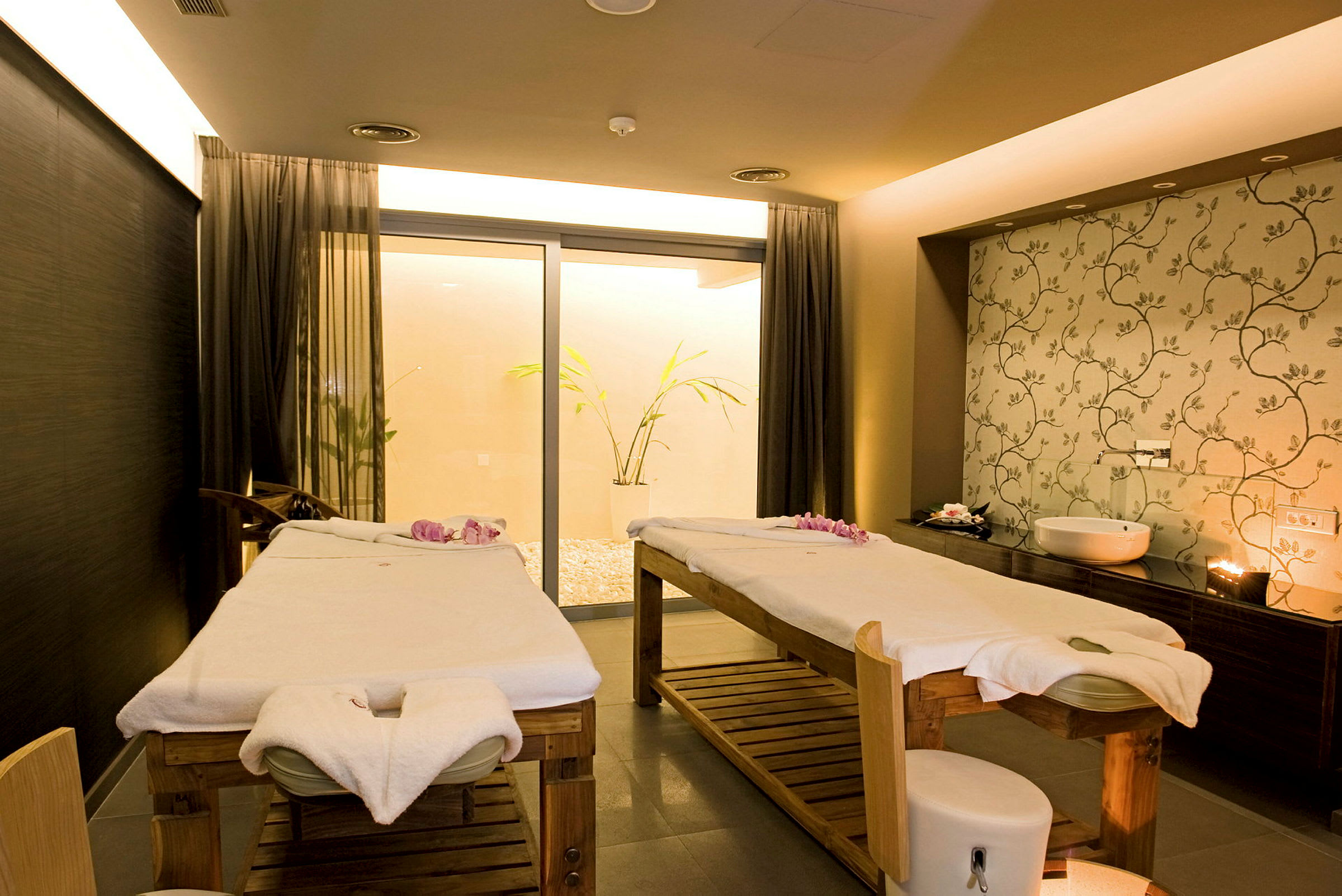 Två massagesängar i ett spa, dekorerade med handdukar och blommor. (AI-genererad text)