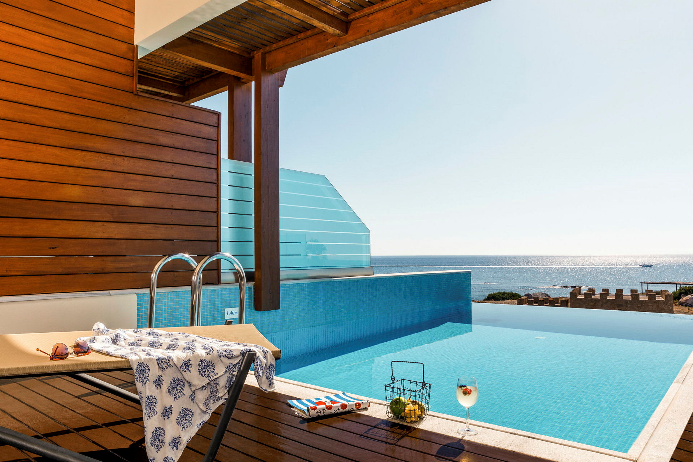 En infinitypool med utsikt över havet, en solstol och en dryck. (AI-genererad text)