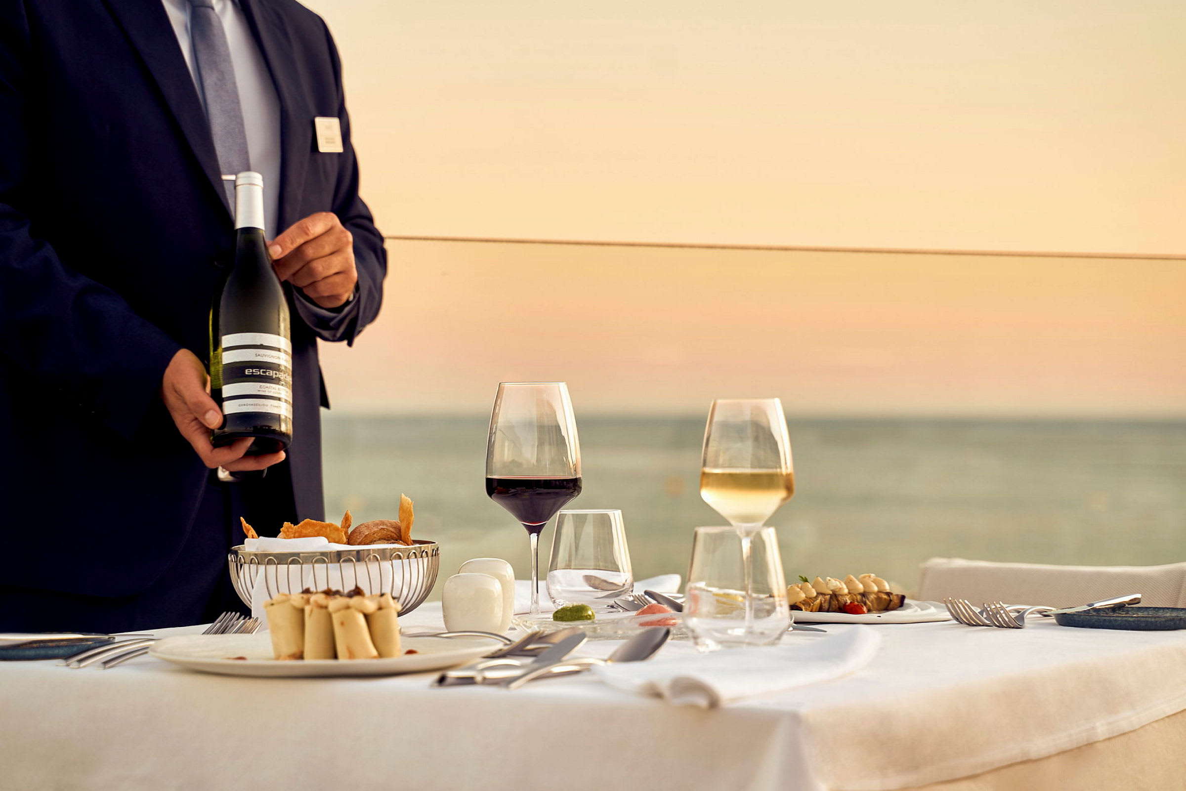 Restaurangbord med servering av mat och dryck vid solnedgång. (AI-genererad text)