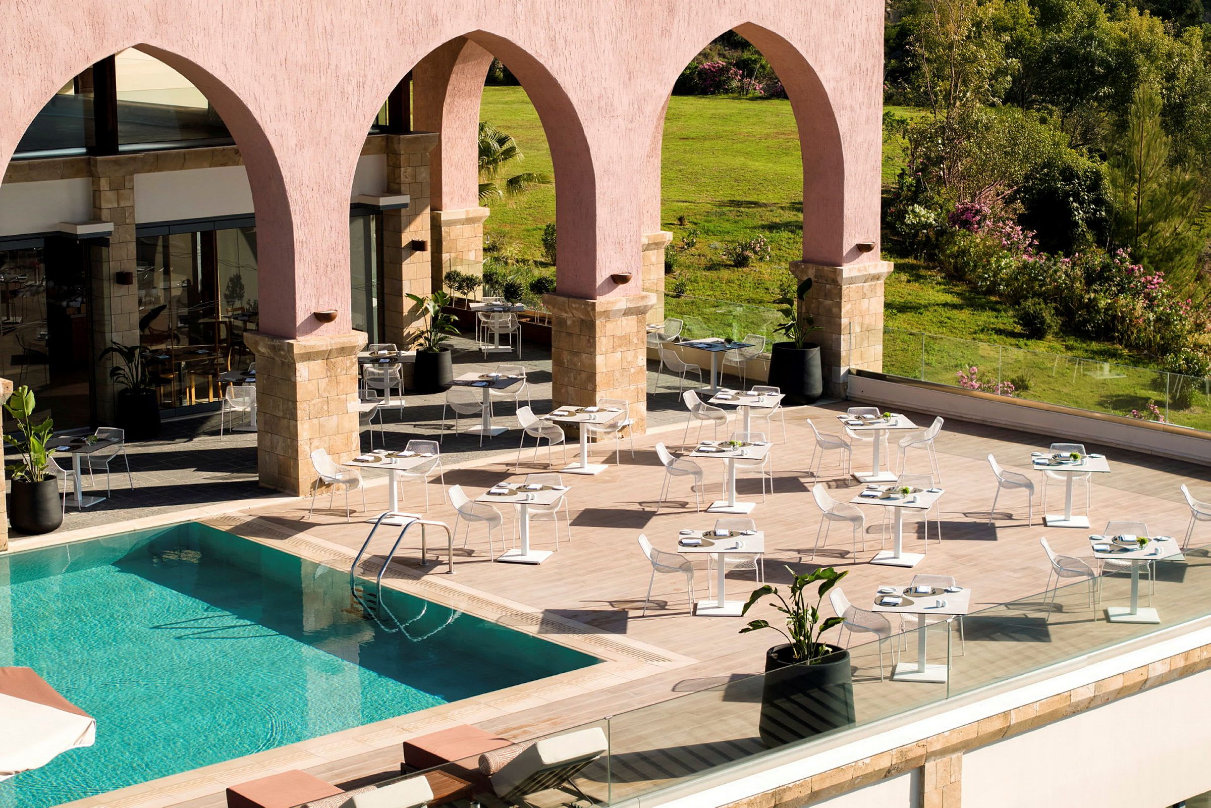 Utomhusrestaurang med pool och grönska i bakgrunden. (AI-genererad text)