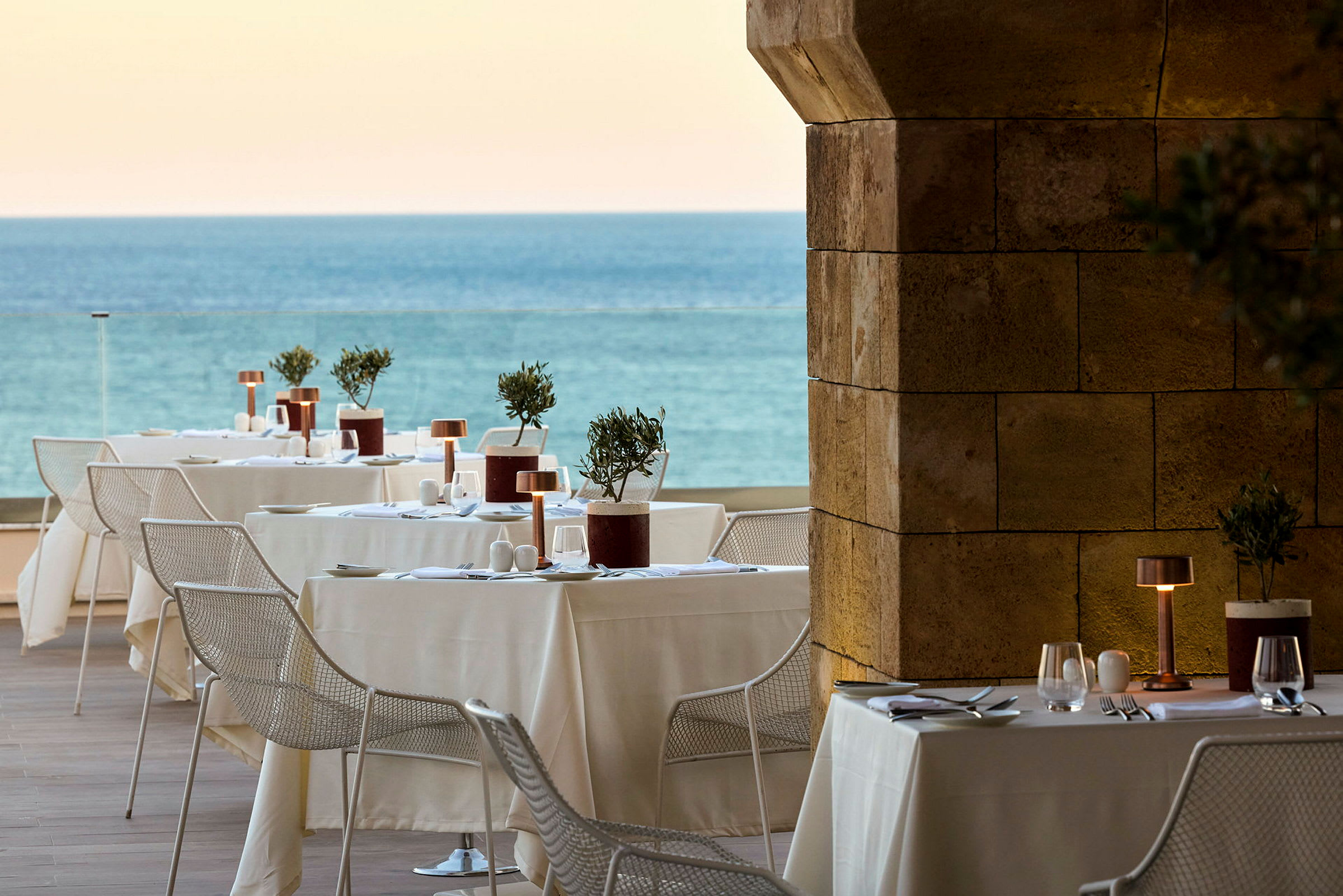 En utomhusrestaurang med dukade bord och utsikt över havet. (AI-genererad text)