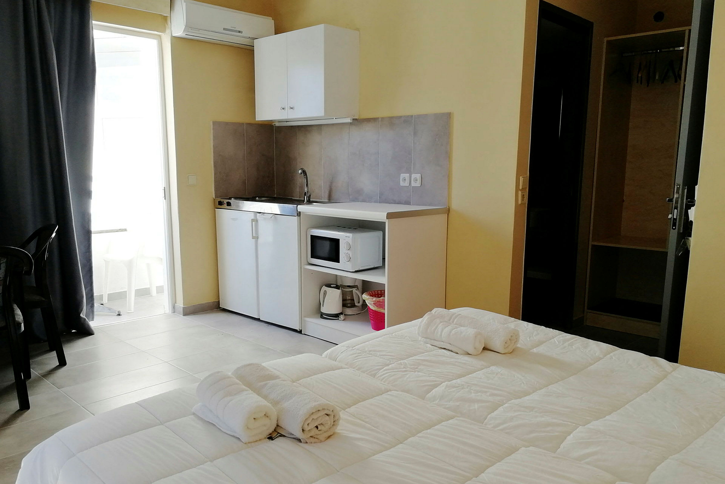 Hotellrum med en mindre köksdel, säng med handdukar samt ett skåp. (AI-genererad text)
