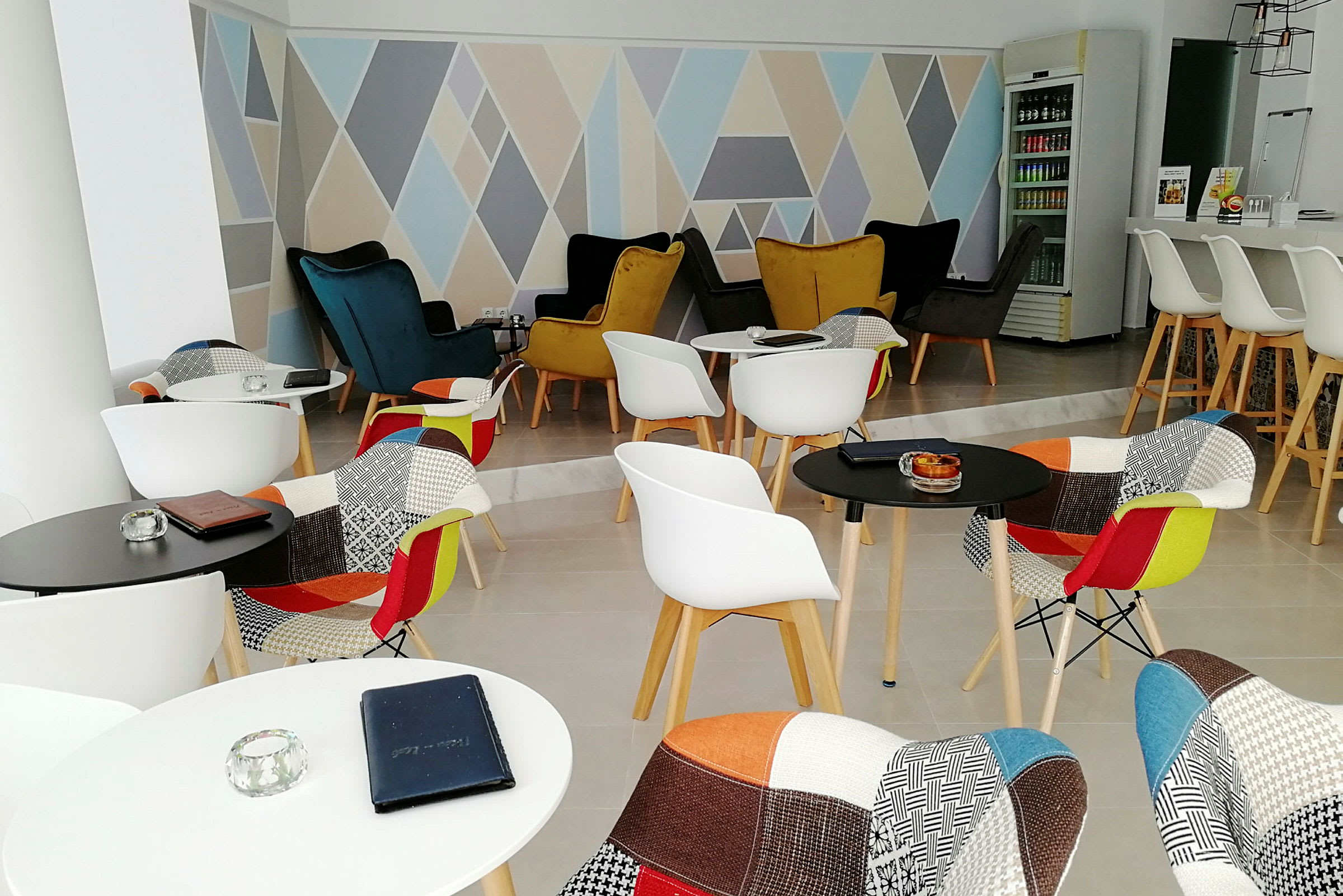 En modern lounge med färgglada stolar och geometriska mönster på väggen. (AI-genererad text)