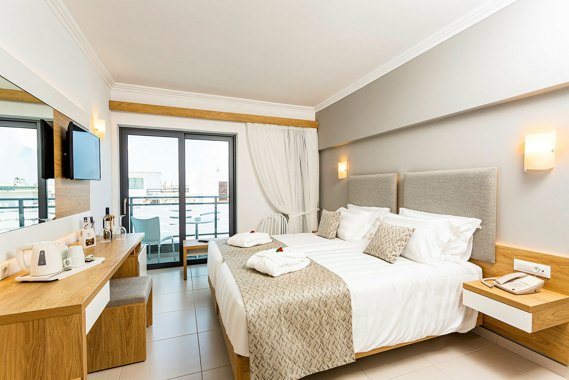 Modernt hotellrum med dubbelsäng, skrivbord och balkong. (AI-genererad text)