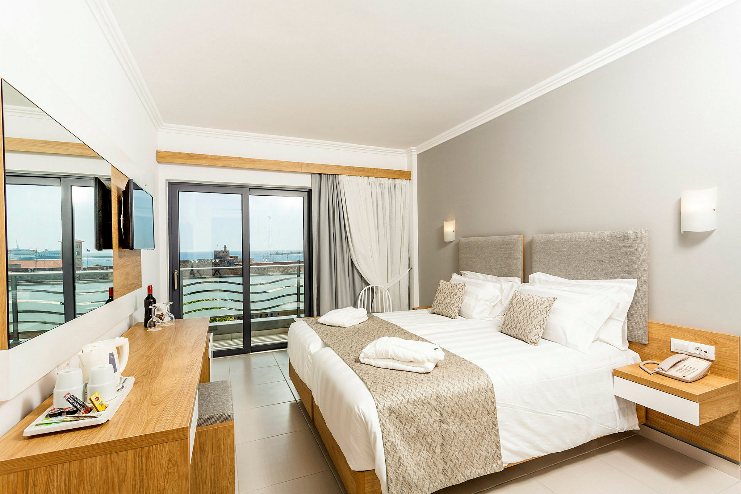 Ett hotellrum med en stor säng, ljusa möbler, och en balkong med utsikt. (AI-genererad text)