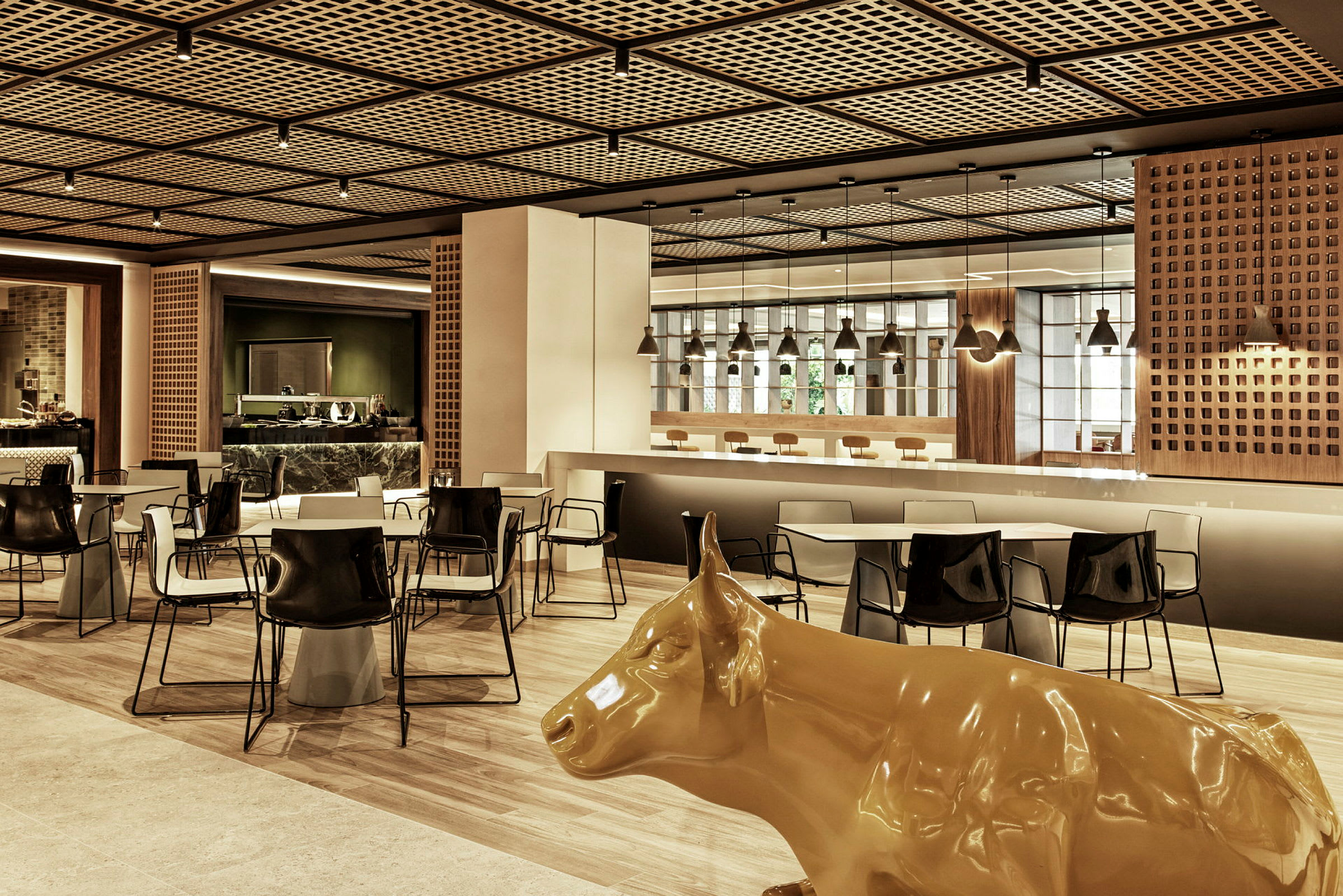 En modern restaurang med bord, stolar och en gul staty av en ko. (AI-genererad text)