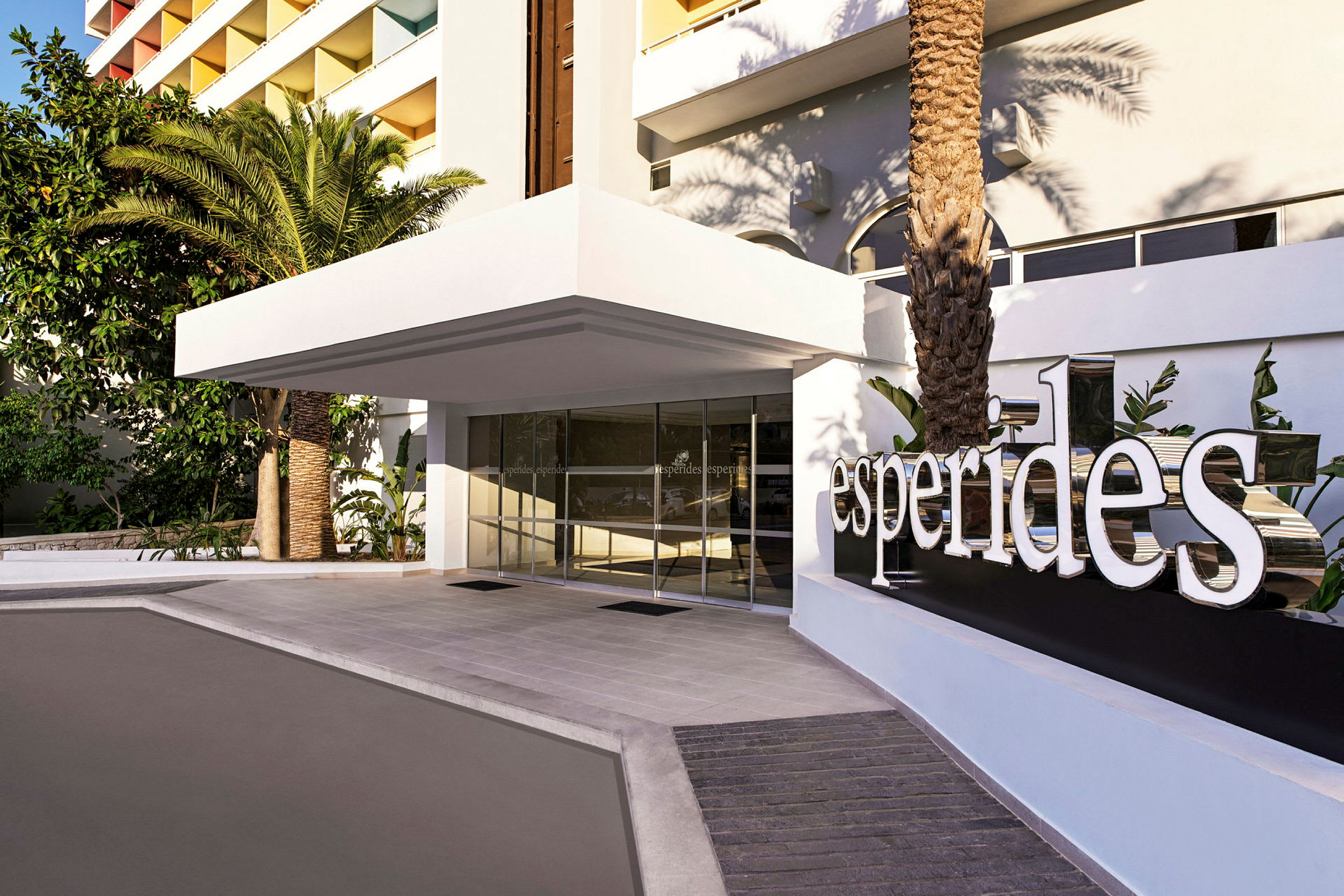 Hotellentré med vit skylt som visar texten "Esperides" och omgivande grönska. (AI-genererad text)